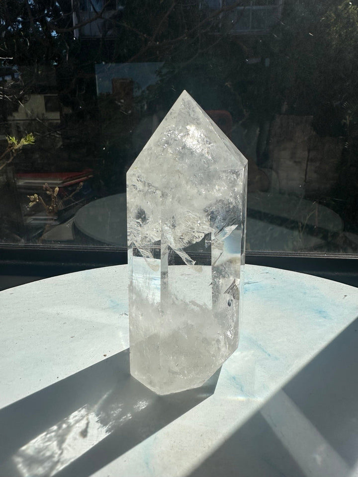 Brazilian Clear Quartz tower number 2 in sunlight, with polished facets, sweeping white internal veils and a cloudy base