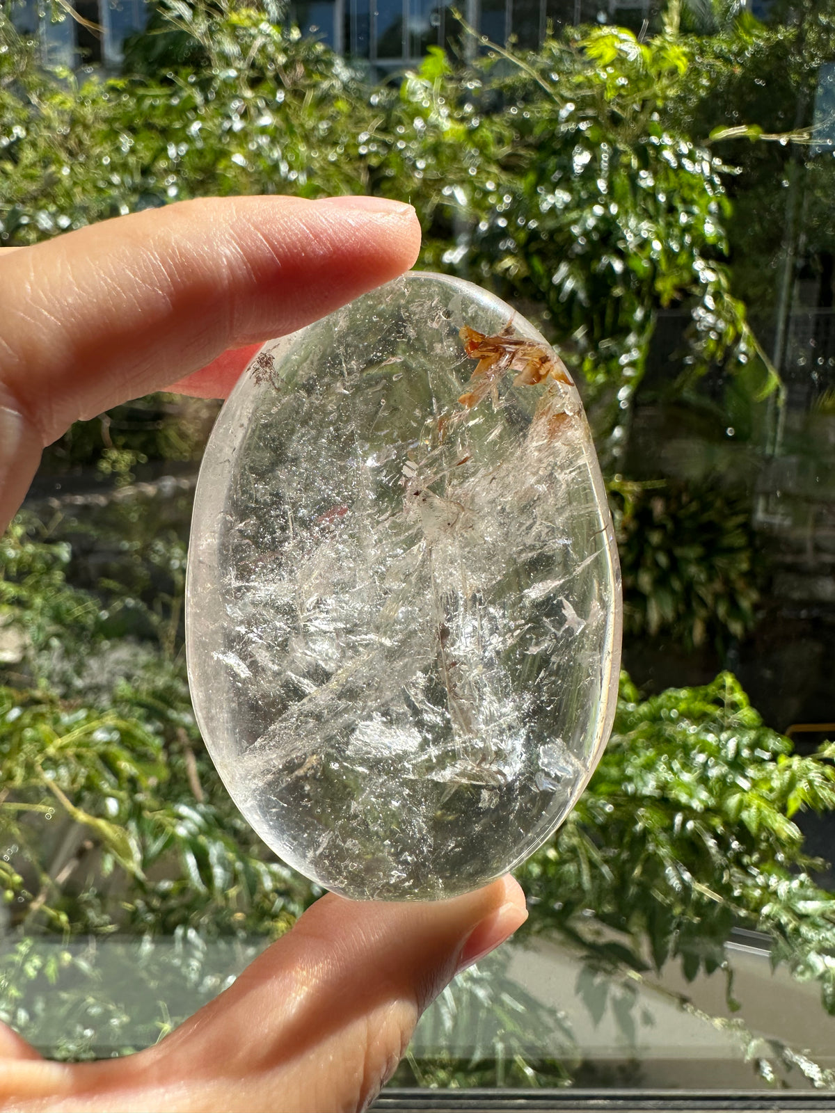 Clear Quartz palm stone showing natural inclusions