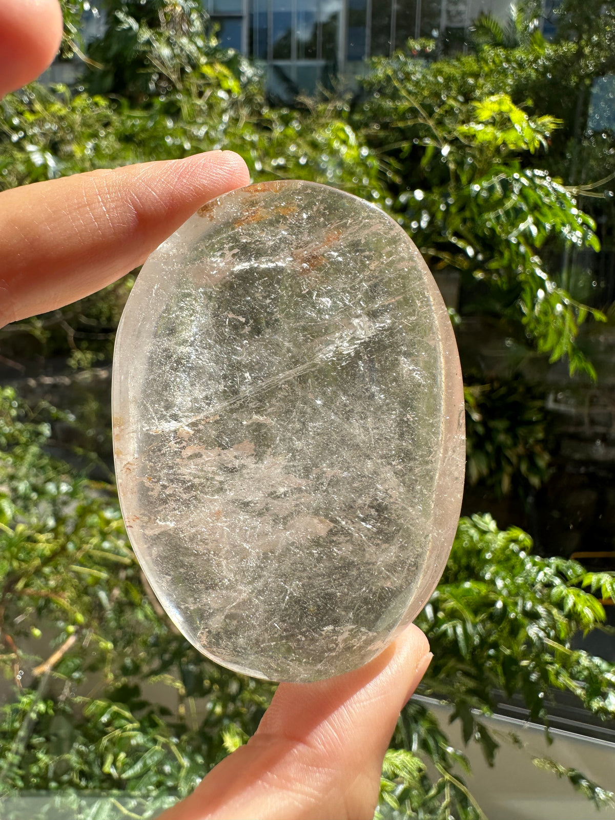 Polished Clear Quartz palm stone photographed in natural light