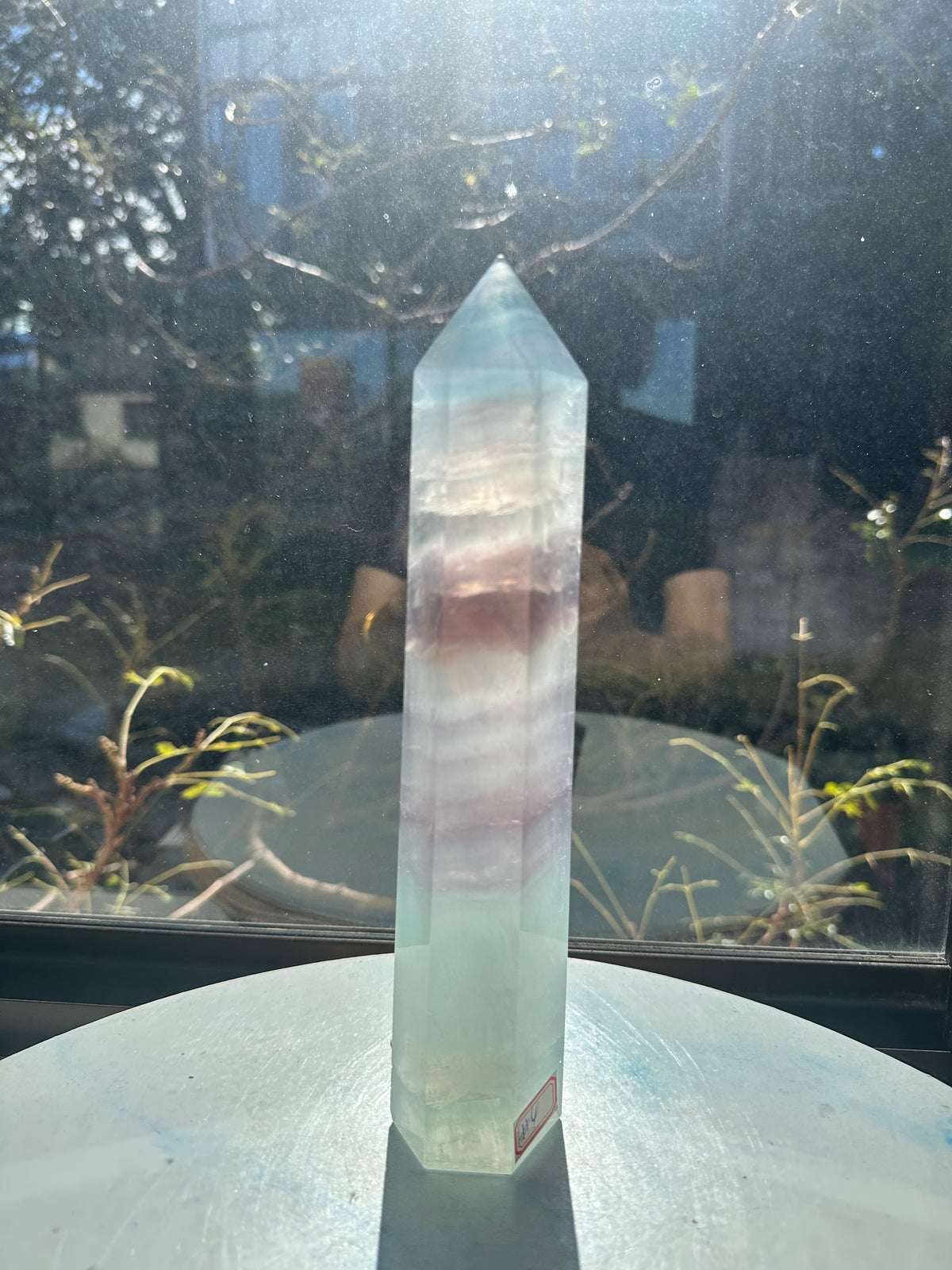 Translucent 23cm tall green fluorite point with prominent horizontal growth layers and a light-reflecting finish, weighing 0.973kg.
