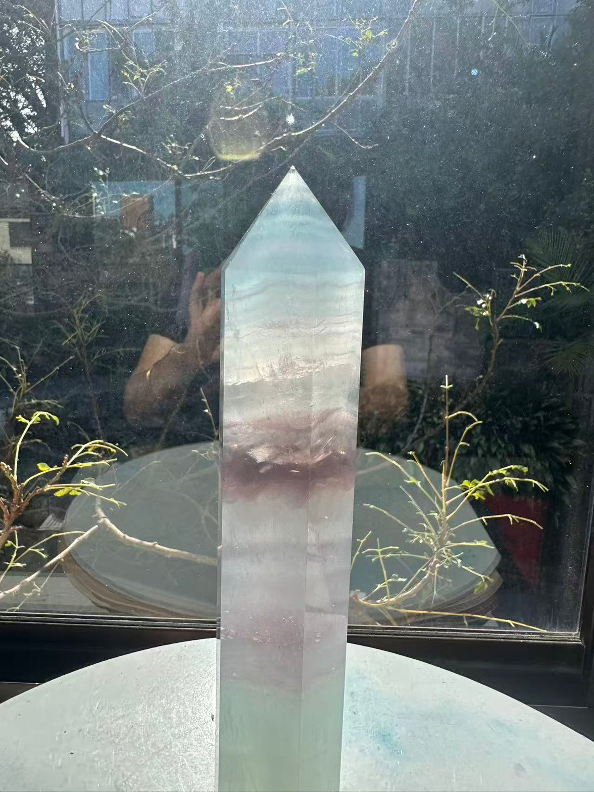 Translucent 23cm tall green fluorite point with prominent horizontal growth layers and a light-reflecting finish, weighing 0.973kg.
