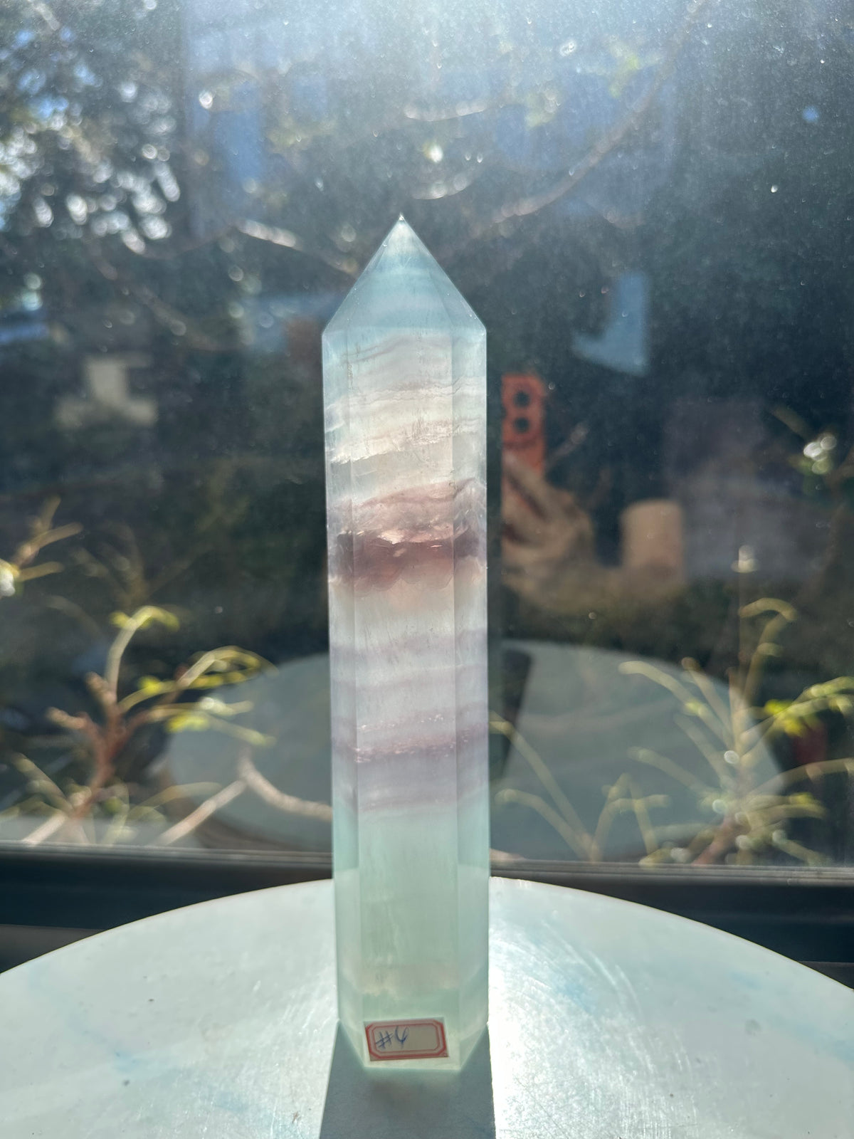 Translucent 23cm tall green fluorite point with prominent horizontal growth layers and a light-reflecting finish, weighing 0.973kg.