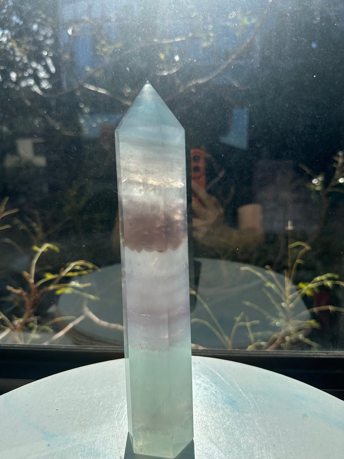 Translucent 23cm tall green fluorite point with prominent horizontal growth layers and a light-reflecting finish, weighing 0.973kg.