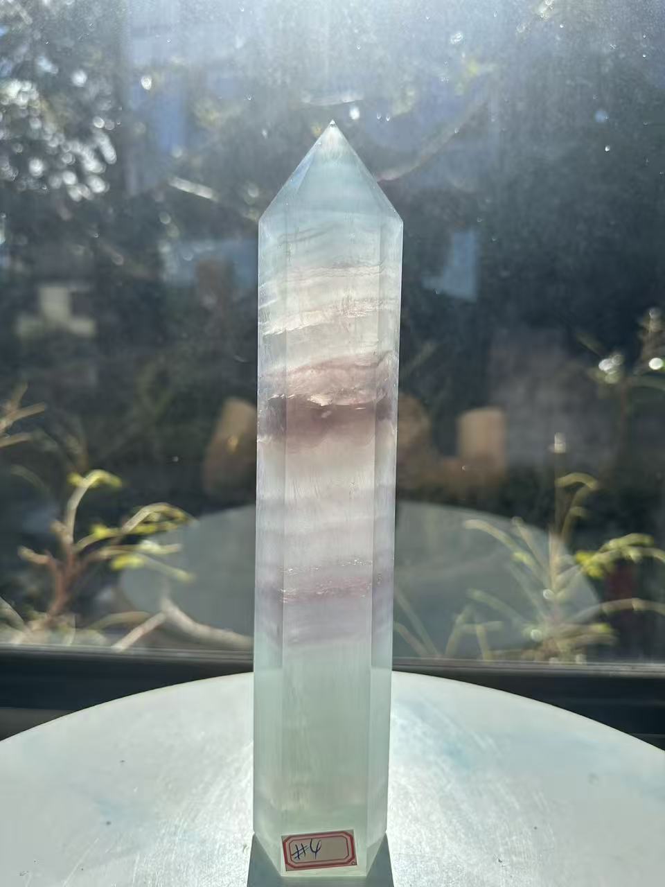 Translucent 23cm tall green fluorite point with prominent horizontal growth layers and a light-reflecting finish, weighing 0.973kg.
