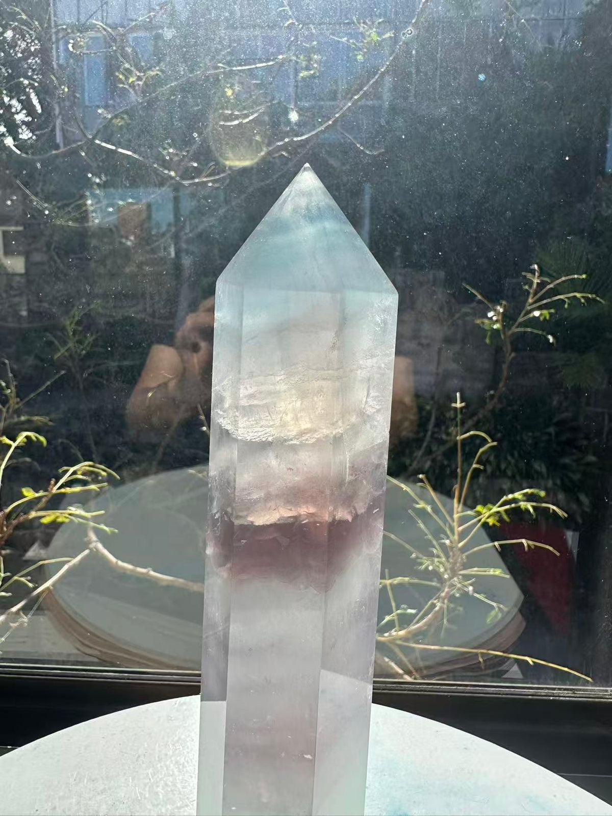 Translucent 23cm tall green fluorite point with prominent horizontal growth layers and a light-reflecting finish, weighing 0.973kg.