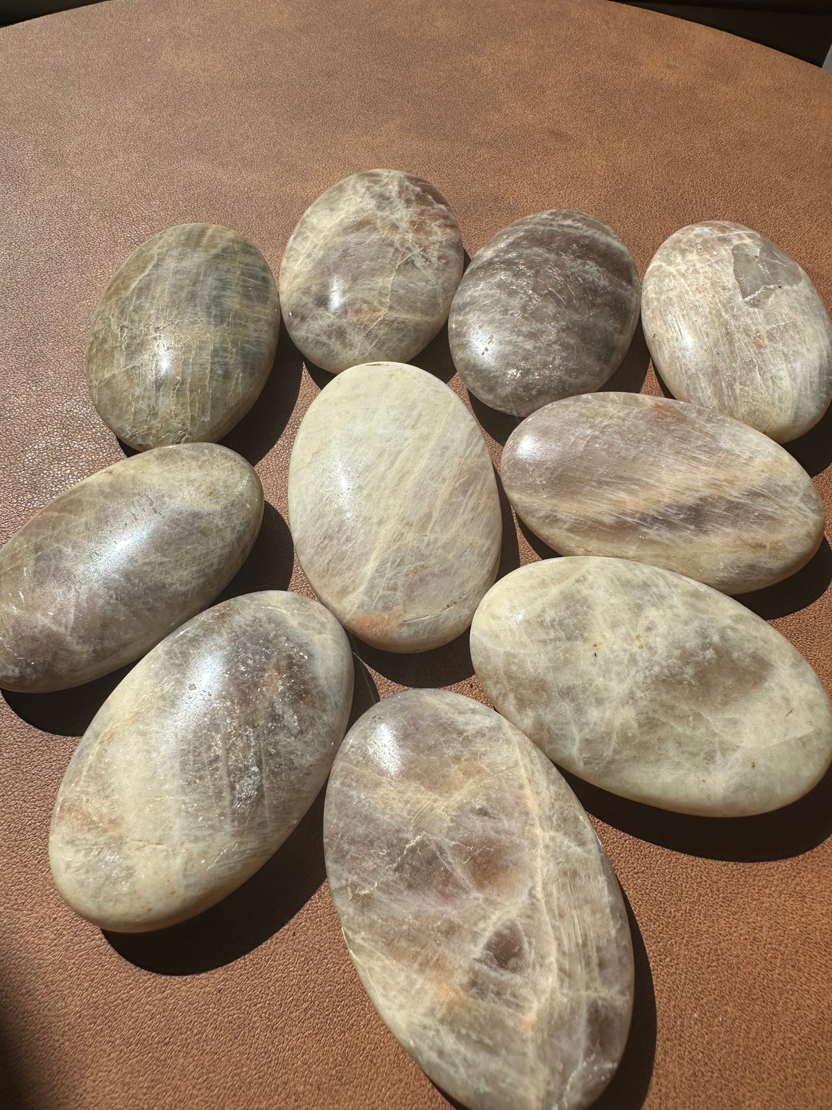 Rainbow Moonstone palm stone 5–6cm with natural blue flash on polished white surface