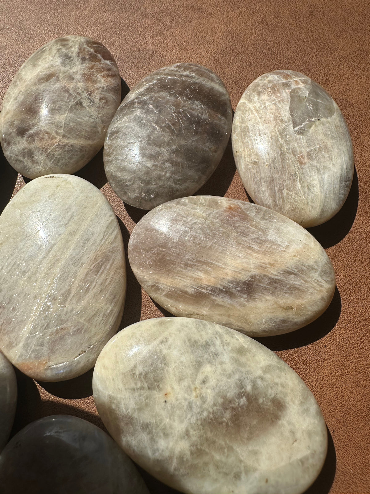 Polished Rainbow Moonstone palm stone showing blue-to-rainbow flash under directional light