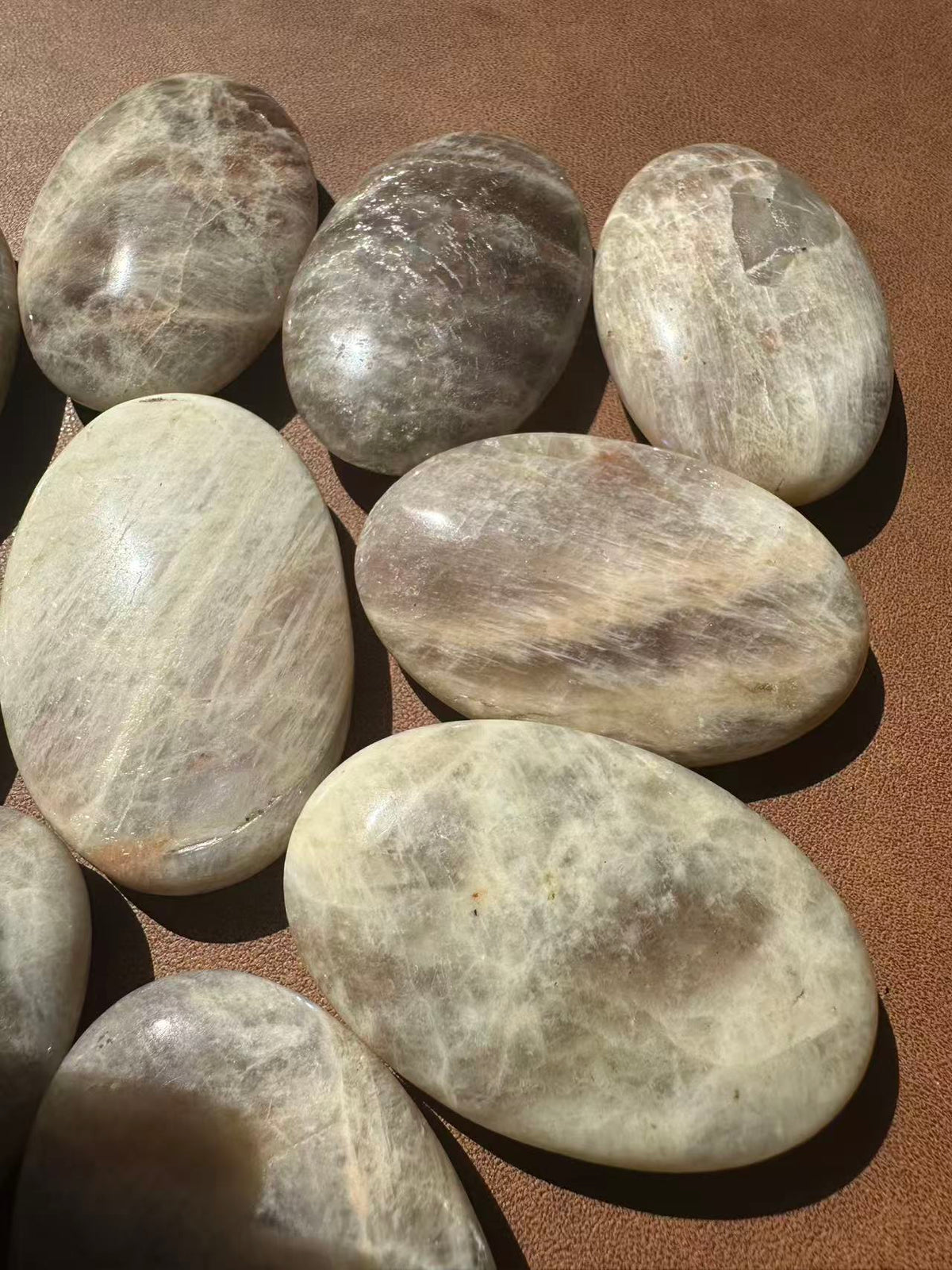 Rainbow Moonstone palm stone angled to reveal blue flash and natural mineral pattern