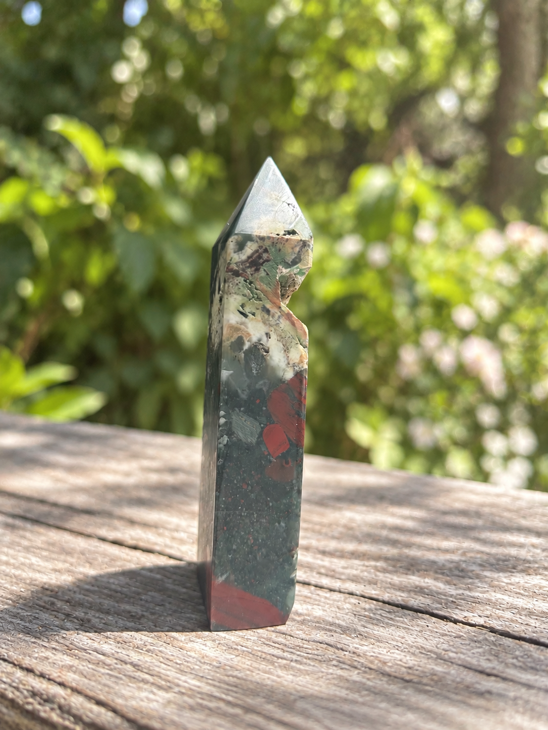 Narrow side of 16cm African bloodstone point showing the open cavity cutting into its silhouette and subdued red markings