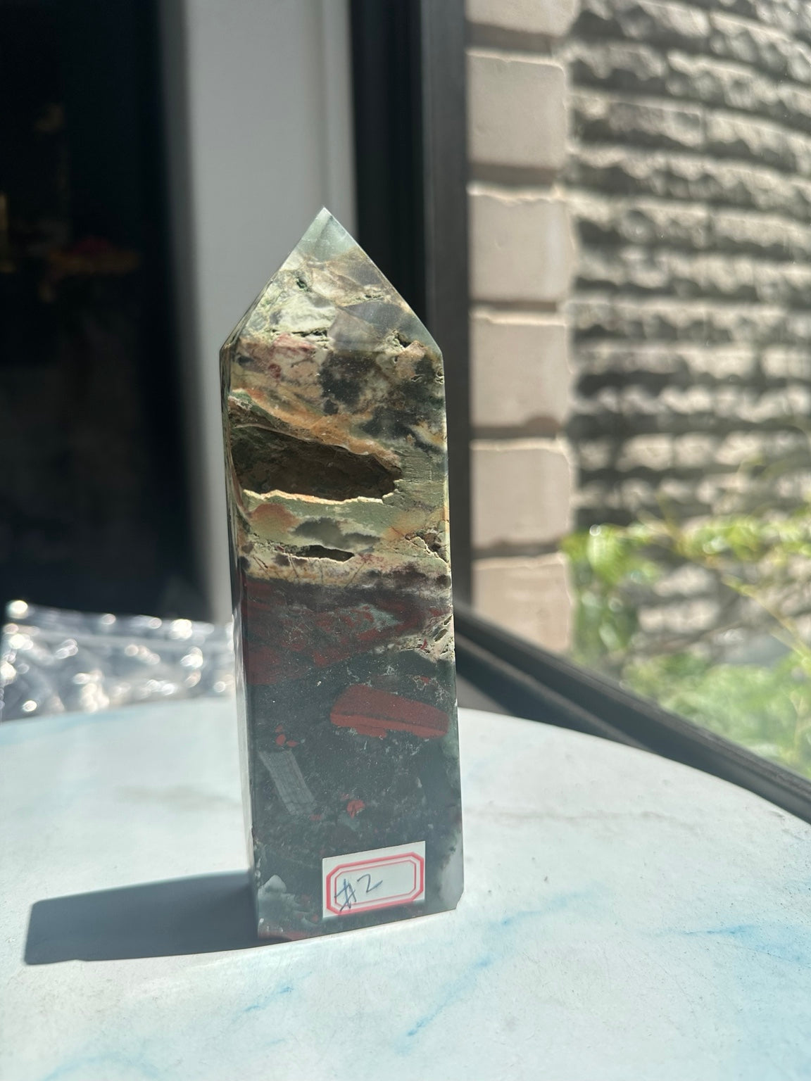 Unedited original photograph of exact African bloodstone tower No.2 showing its natural cavities and red number label in window light
