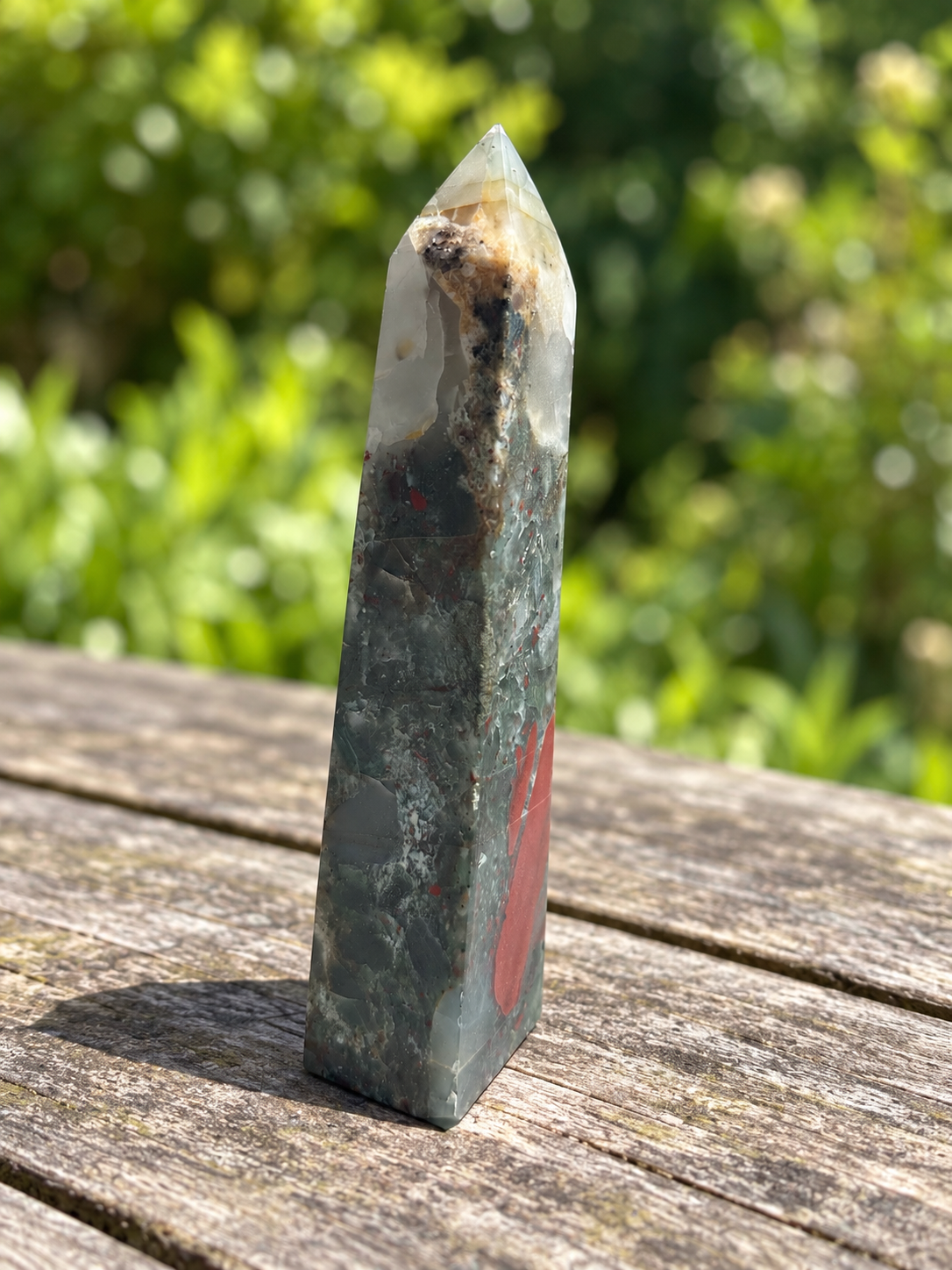 Side view of No.4 African bloodstone tower showing the pale mineral colour zone, darker inclusions and a long brick-red marking along one edge.