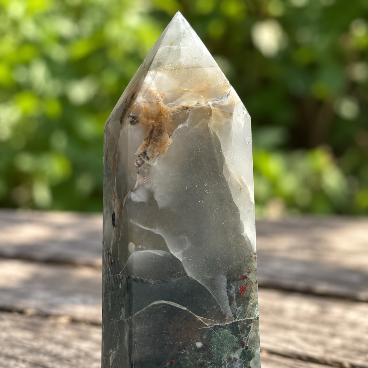 Close-up of No.4 bloodstone tower tip showing cloudy grey and cream zones, warm tan band, tiny dark inclusions and visible surface detail.