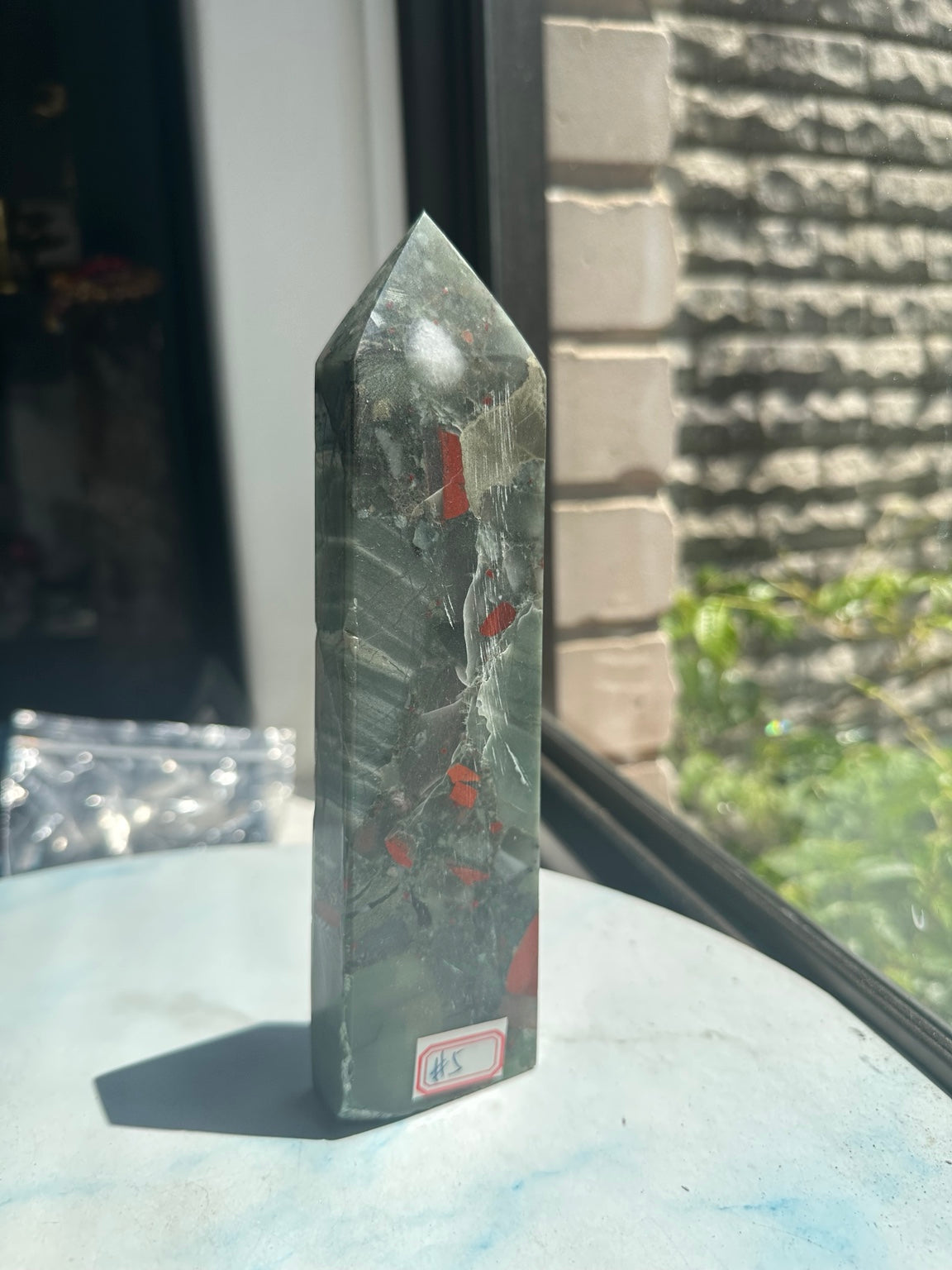 Unedited original standing photograph of No.5 tower showing the 19cm pointed form, grey-green stone and scattered red markings.