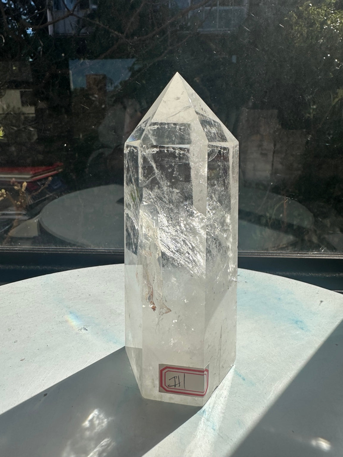 Final rotated view of the same crystal showing its pointed top, transparent upper section, milky base and red inventory sticker.