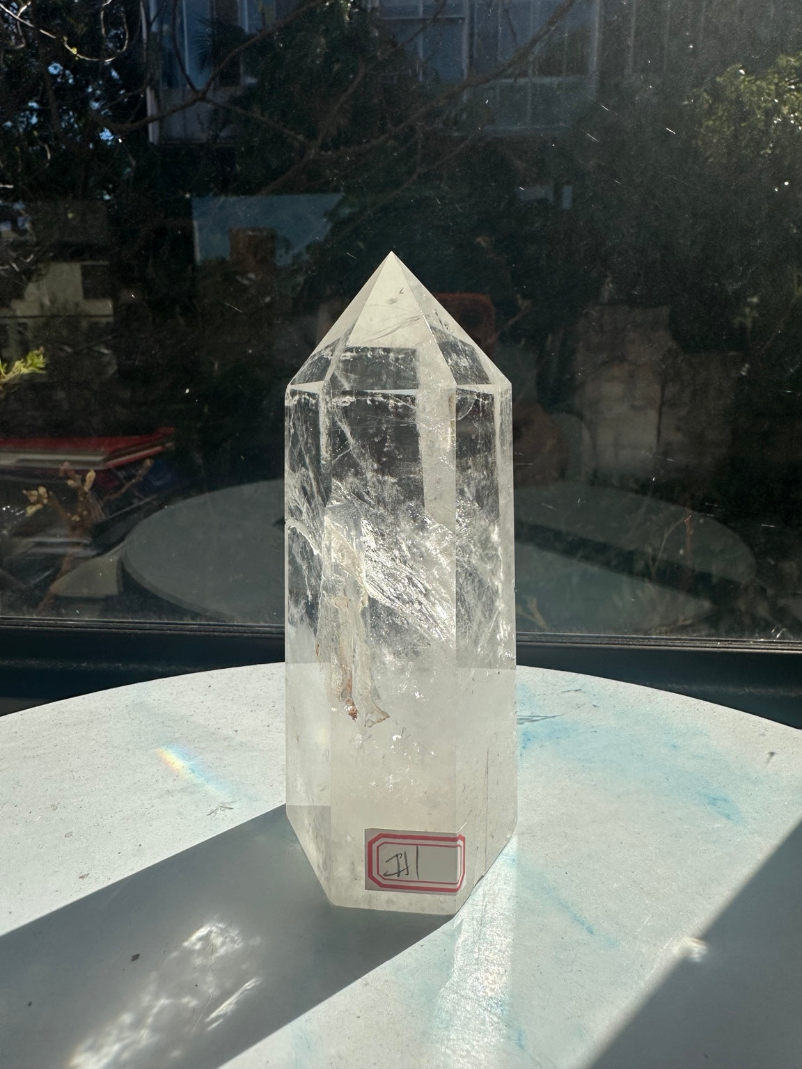 Front view of the exact quartz tower with a red inventory sticker near its base, clear upper section and white internal veils.