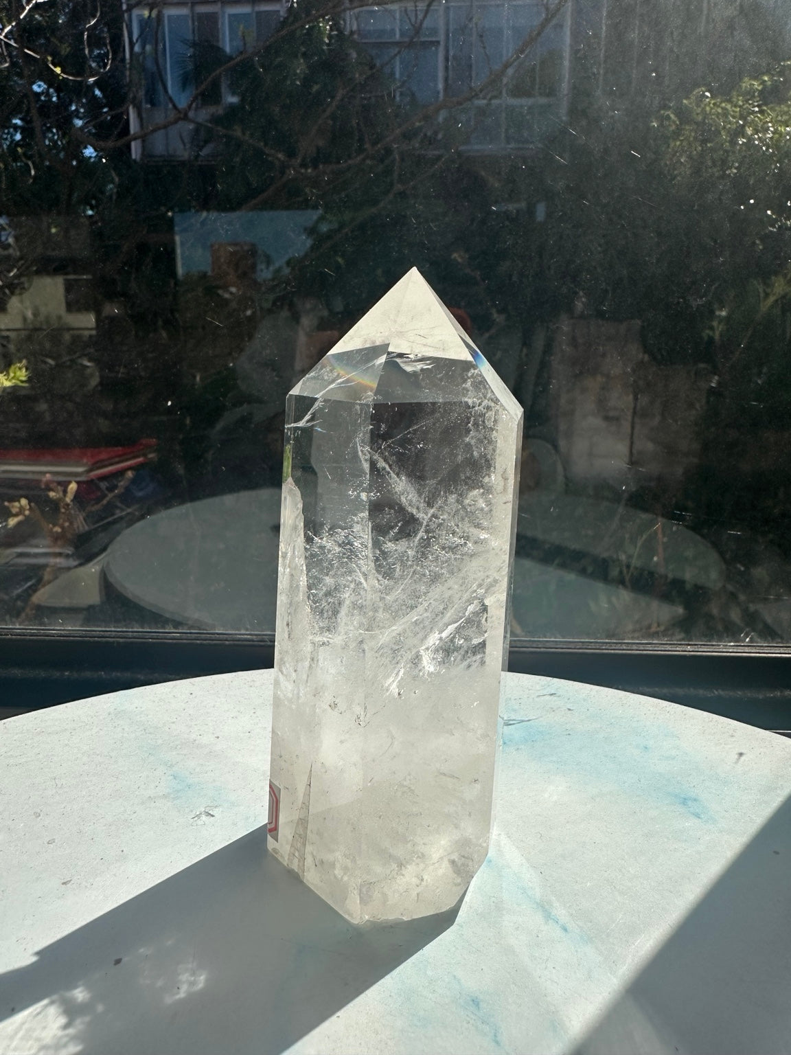 Side angle of the Brazilian clear quartz tower, highlighting white veils and internal fractures between broad polished faces.
