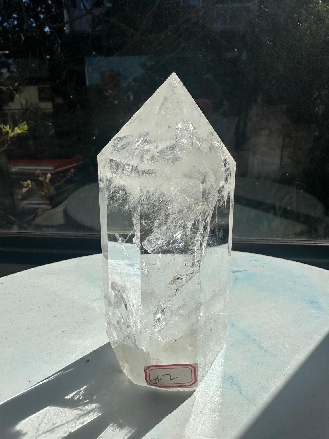 Front view of Brazilian quartz tower #2, with its red inventory label, clear polished faces, cloudy point and layered internal veils.