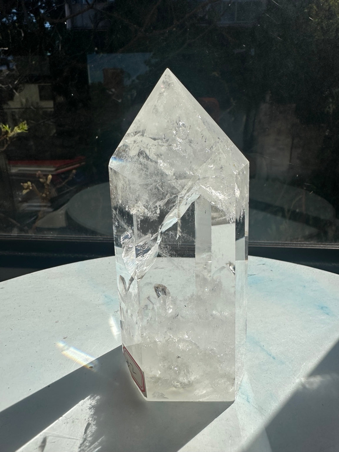 Rotated view of the 624g quartz point showing broad transparent facets, diagonal internal fractures and a cloudy white lower section.
