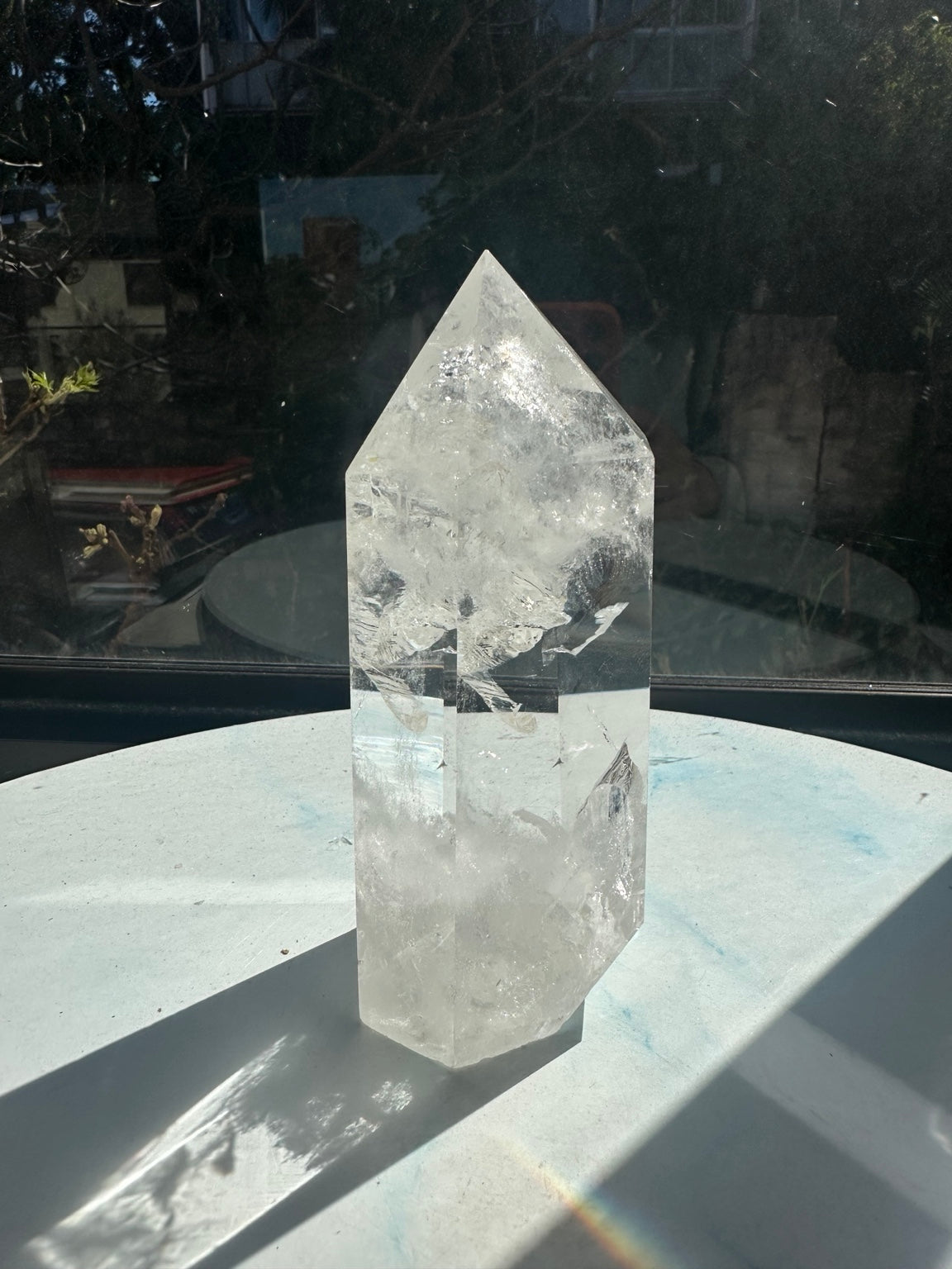 Rear view of quartz tower #2 in natural window light, with bright internal textures and rainbow light cast near its shadow.