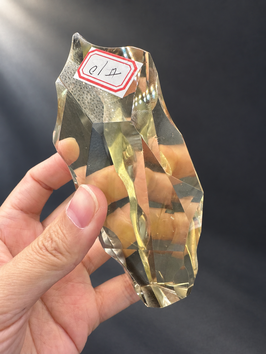 Full handheld view of Brazilian citrine No.10 with its asymmetric fine-cut form