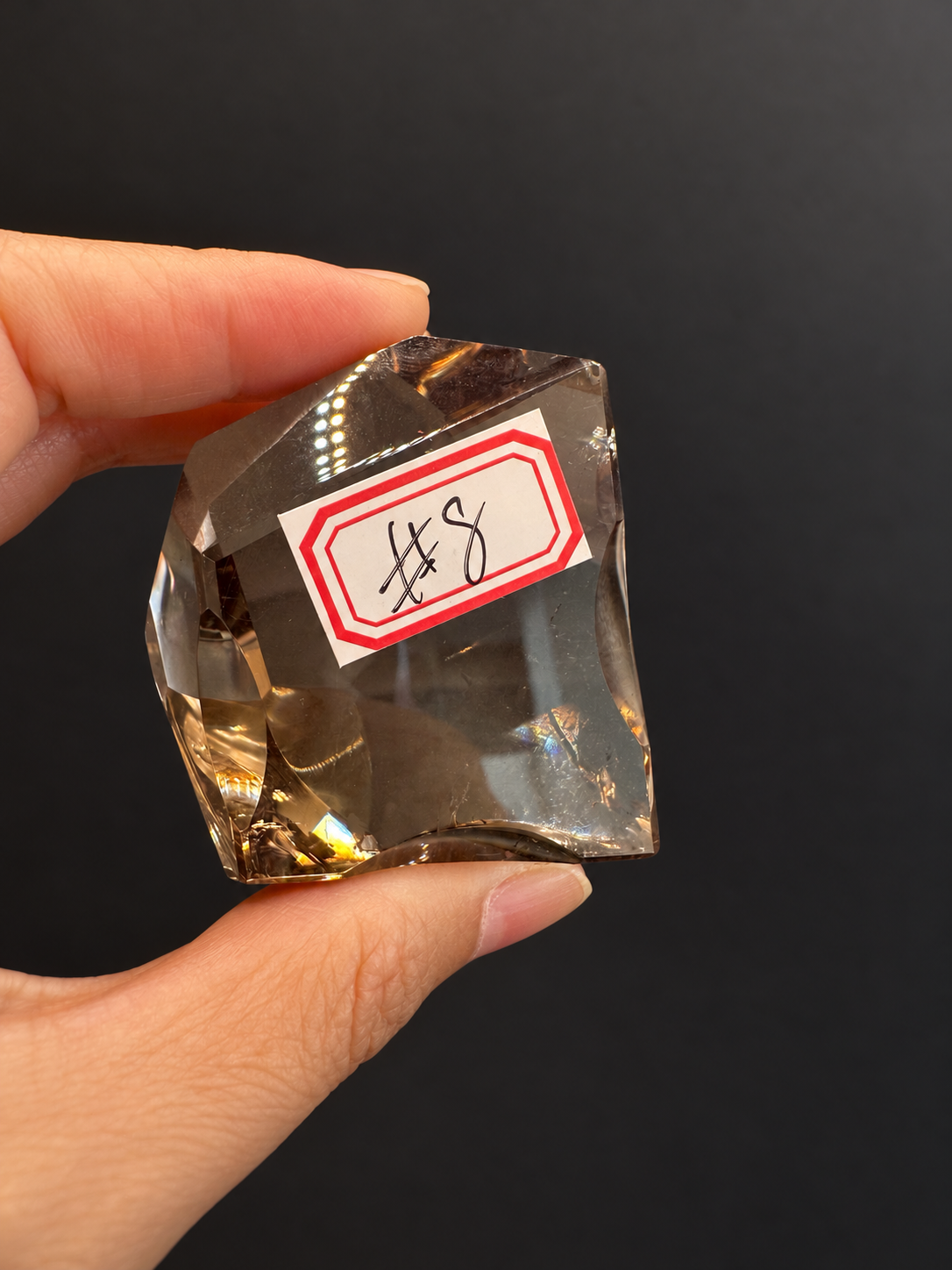 Brazilian citrine freeform No.8, 134g, approx. 5 × 5cm; labelled No.8 front view showing pale smoky-gold transparency, held in the original hand against a charcoal background.