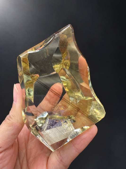 Brazilian citrine freeform No.9, 187g, held in hand showing curved fine-cut facets