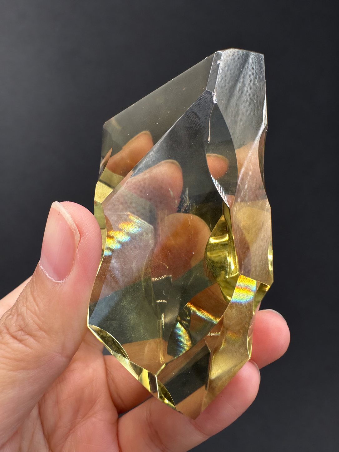 Brazilian citrine freeform No.2, 190g, approximately 8 × 4.4cm; upright side angle with concave edge cuts, golden lower facets and original coloured light reflections, held in the original hand.