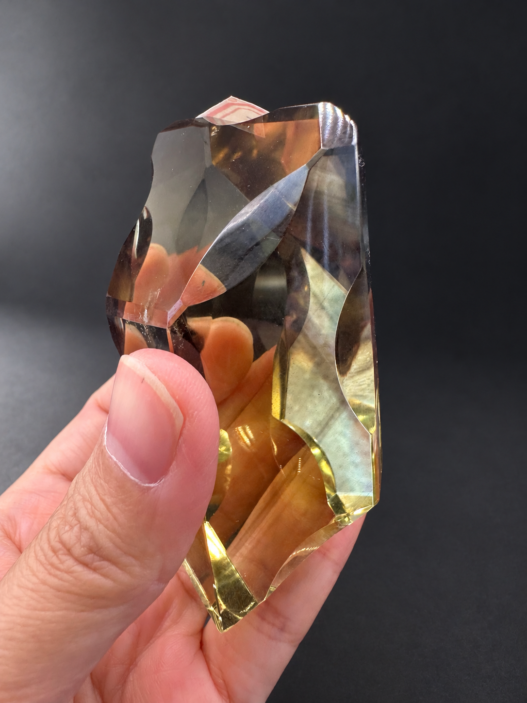 Brazilian citrine freeform No.2, 190g, approximately 8 × 4.4cm; narrow side profile showing flowing cutwork and warm golden edges, held in the original hand.