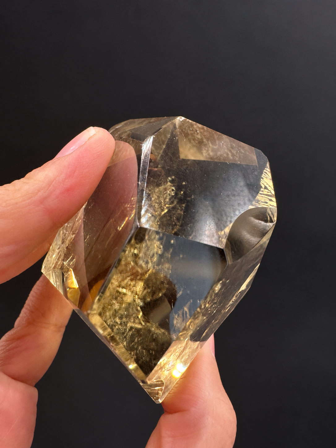 Brazilian citrine freeform No.6, 203g, approximately 6.3 × 5.8cm; side profile showing the depth, polished facets and fingers through the clear window, held in the original hand against a charcoal background.