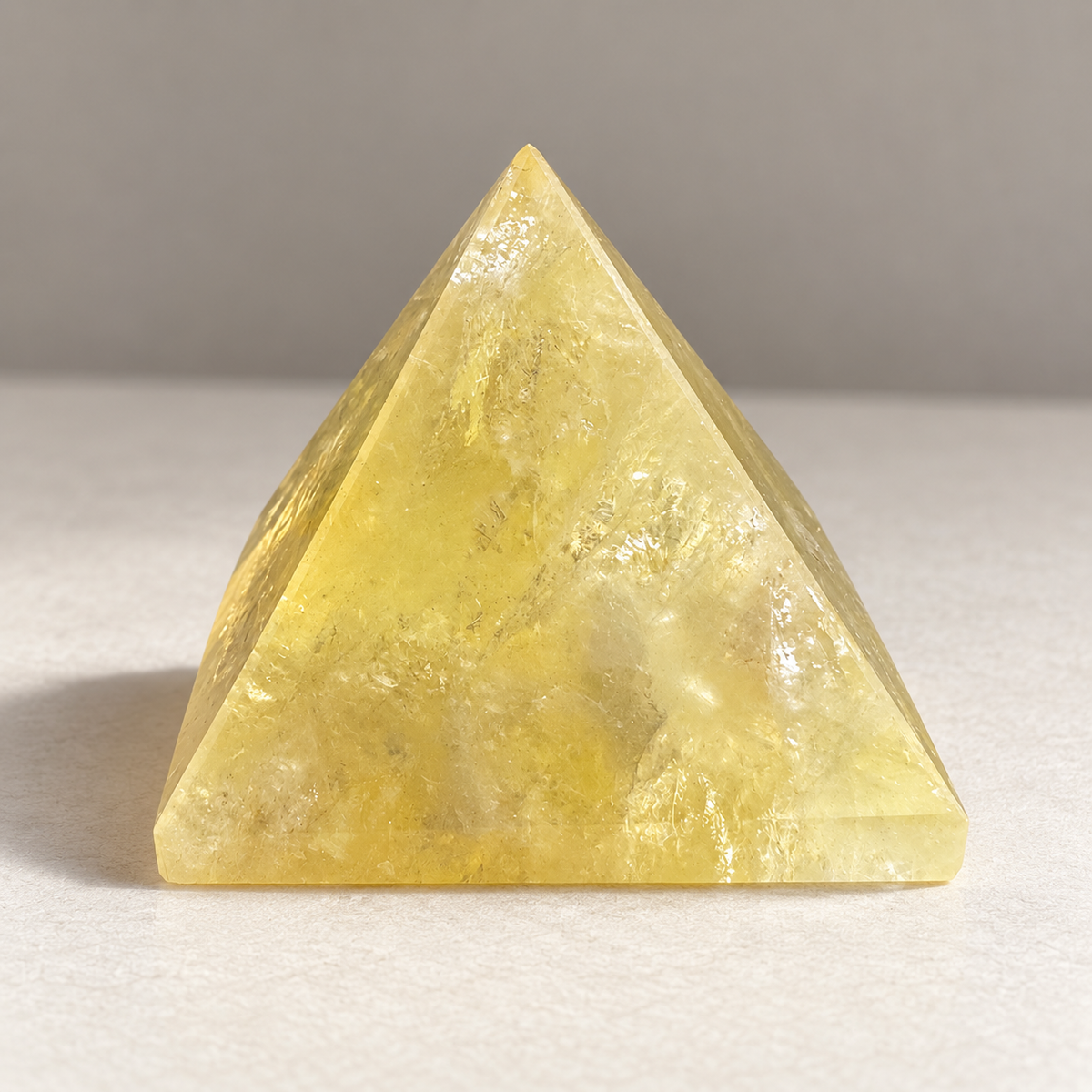 Front view of a polished Brazilian Citrine pyramid showing golden translucency, mineral inclusions and its pyramid shape
