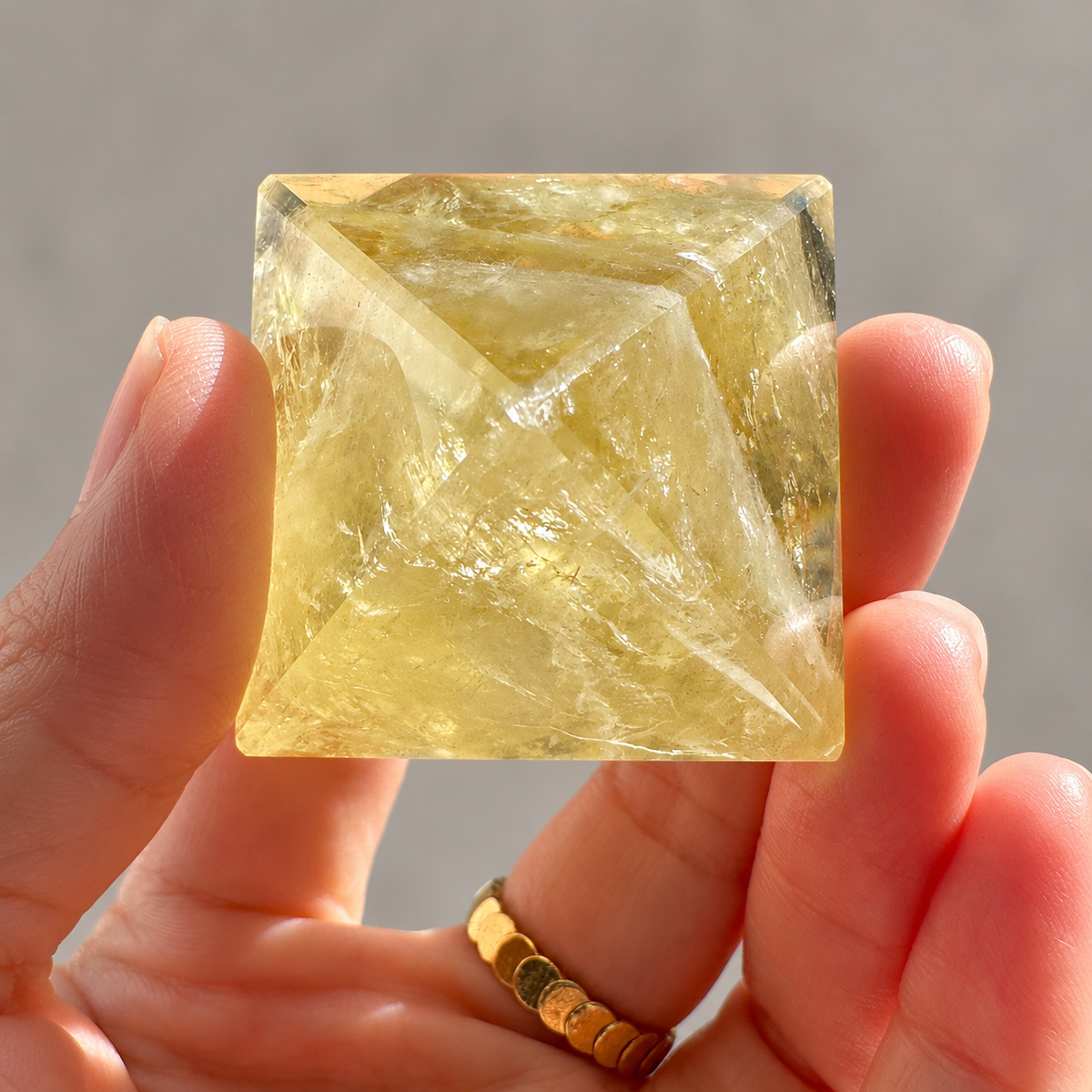Square base of a Brazilian Citrine pyramid held in a hand, showing polished edges and internal fractures