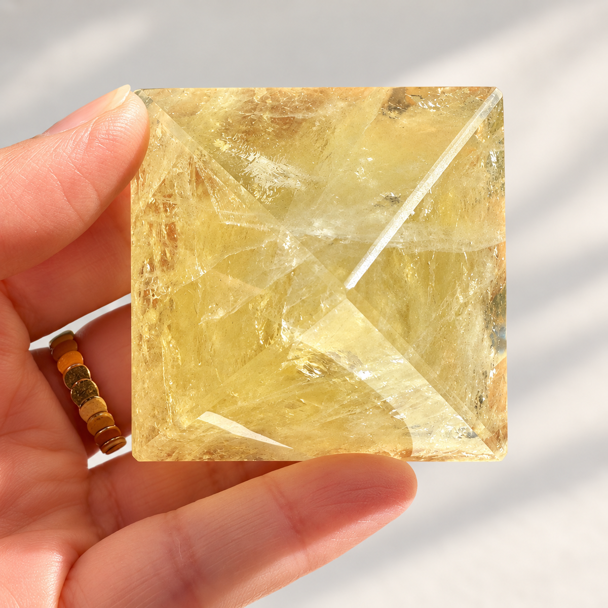 Alternate base view of a polished Brazilian Citrine pyramid showing translucent golden colour and internal facet reflections