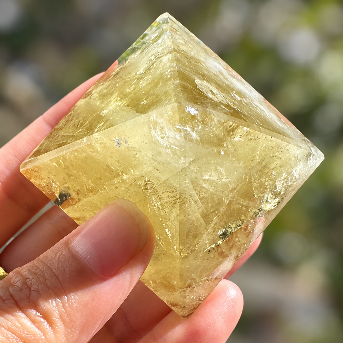 Close-up of a Brazilian Citrine pyramid showing polished facets, cloudy veils and mineral inclusions
