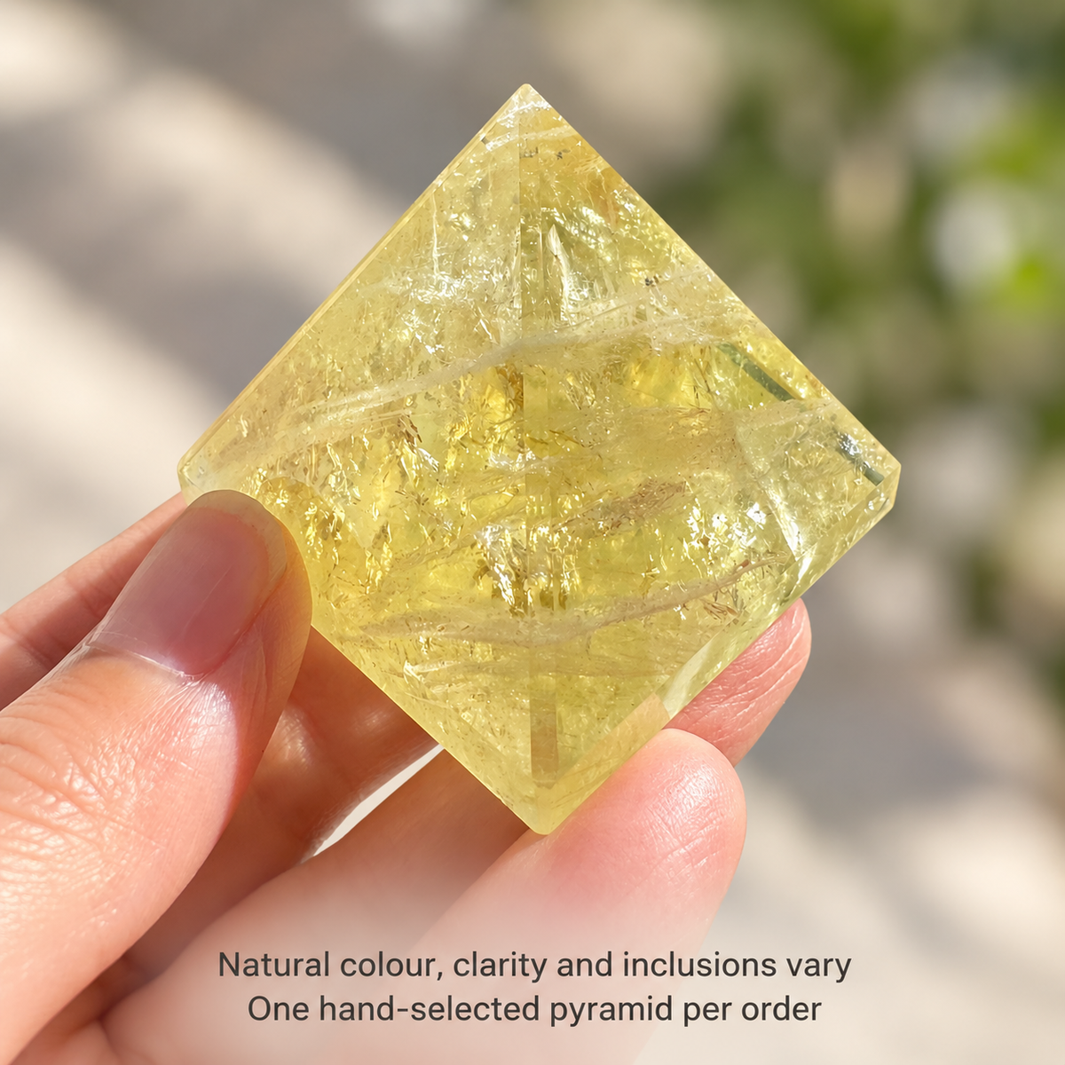 Golden Brazilian Citrine pyramid held at an angle, with a reminder that colour, clarity and inclusions vary naturally