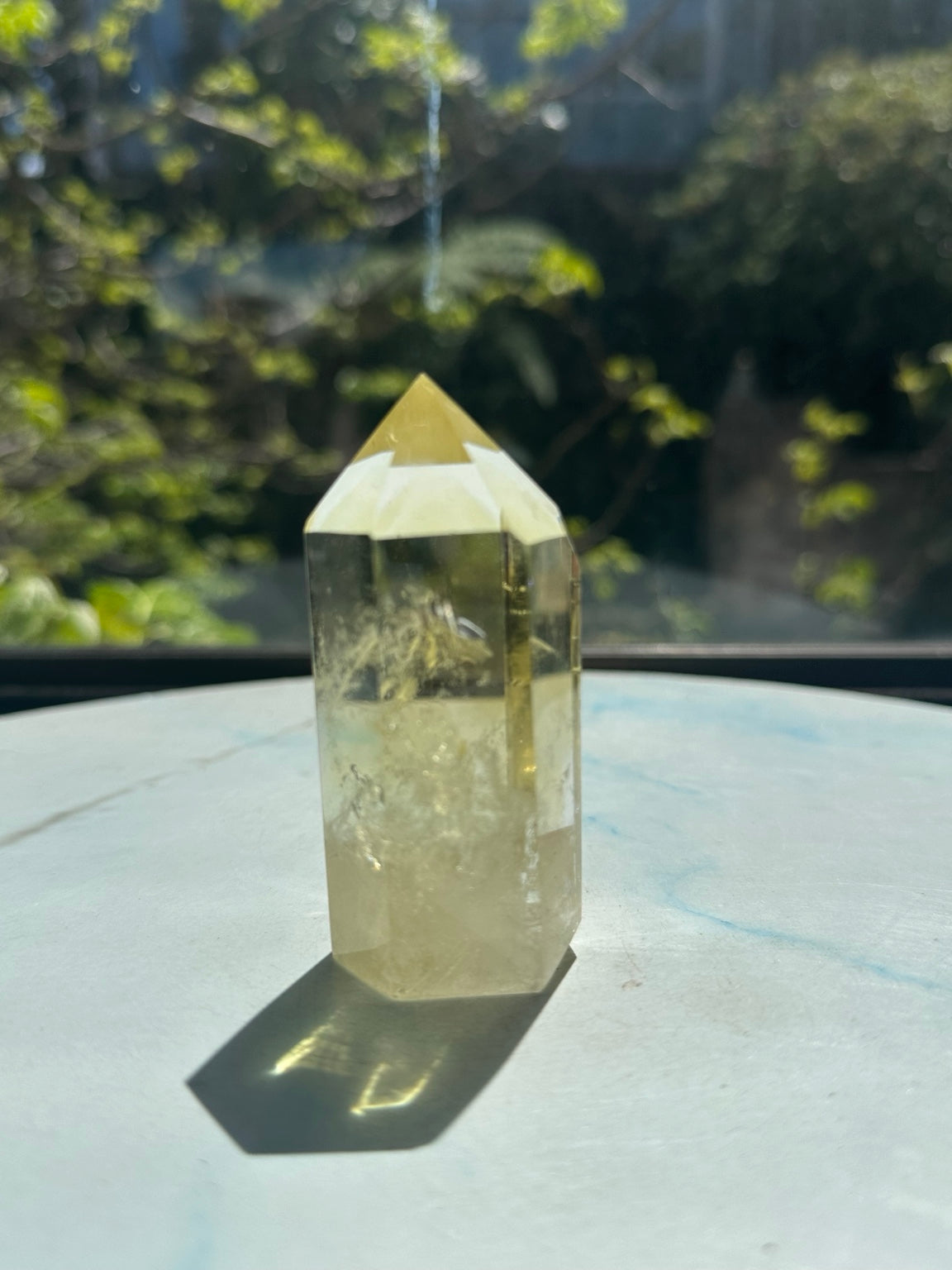 Original natural-sunlight side photograph of Brazilian citrine tower #4 showing the exact stone's pale yellow colour and internal veils