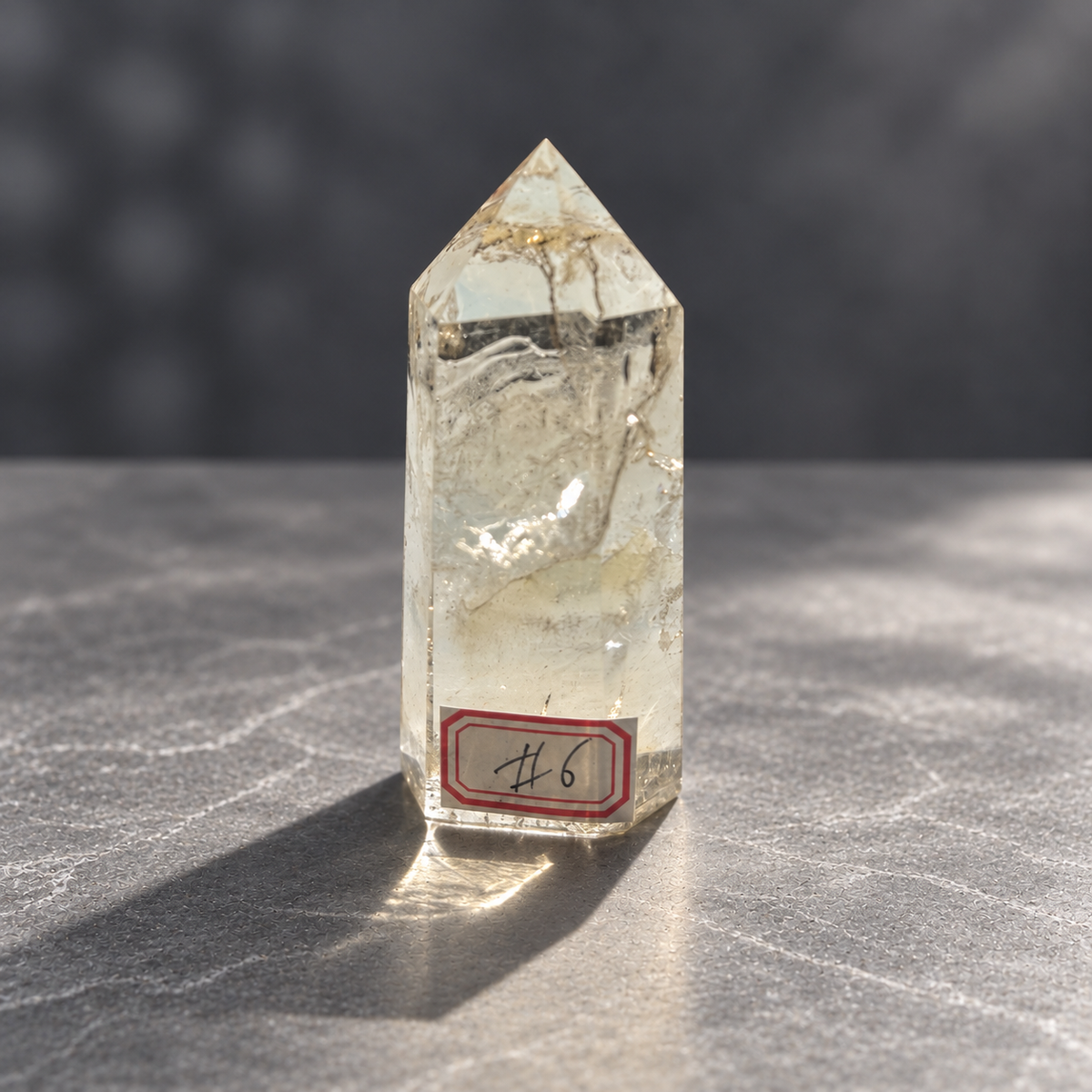 Brazilian pale yellow champagne citrine tower #6, 129g, front view with number 6 label, pale yellow body and rippling natural internal veils