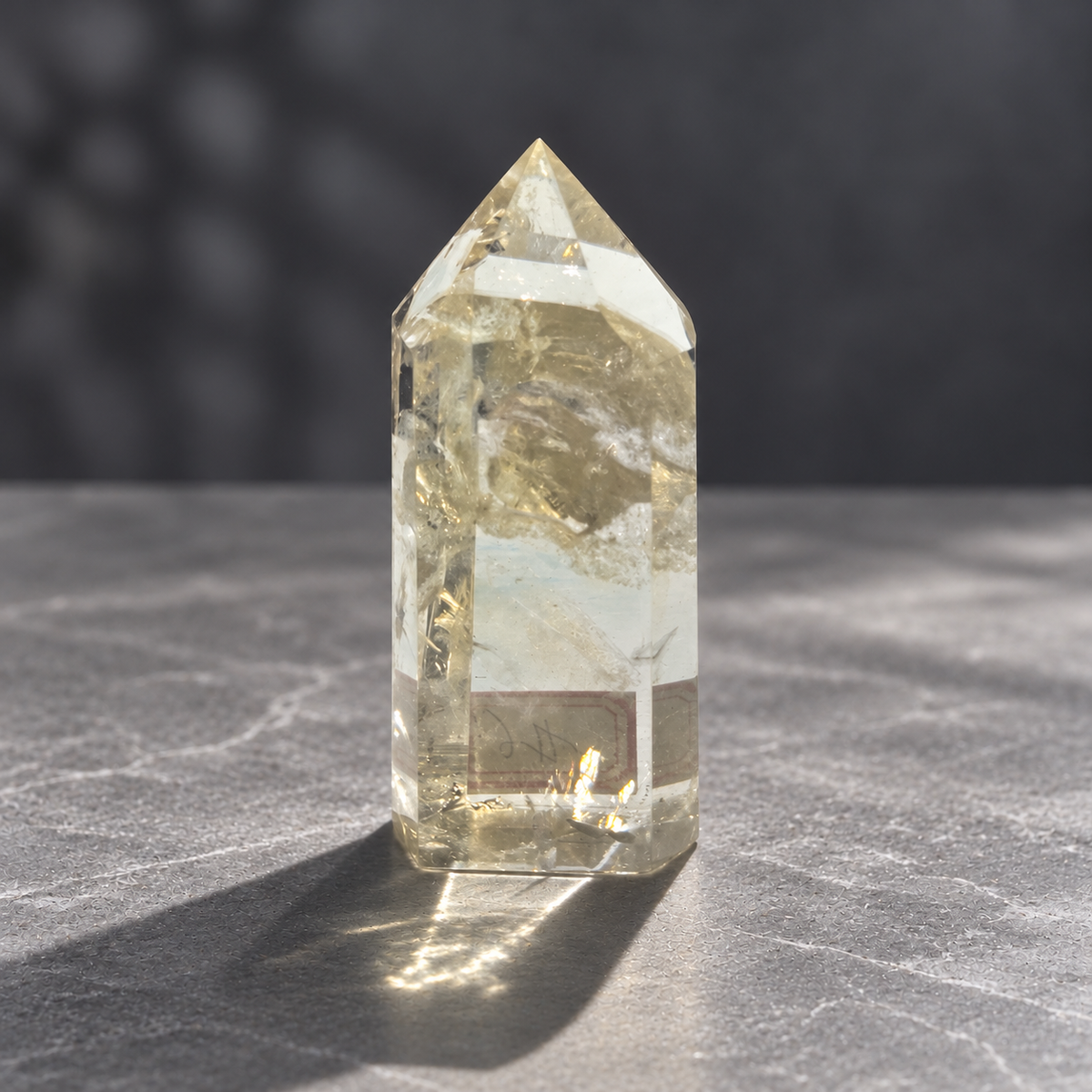 Brazilian pale yellow champagne citrine tower #6, 129g, back view showing natural fractures and original label refracted through the clear lower section