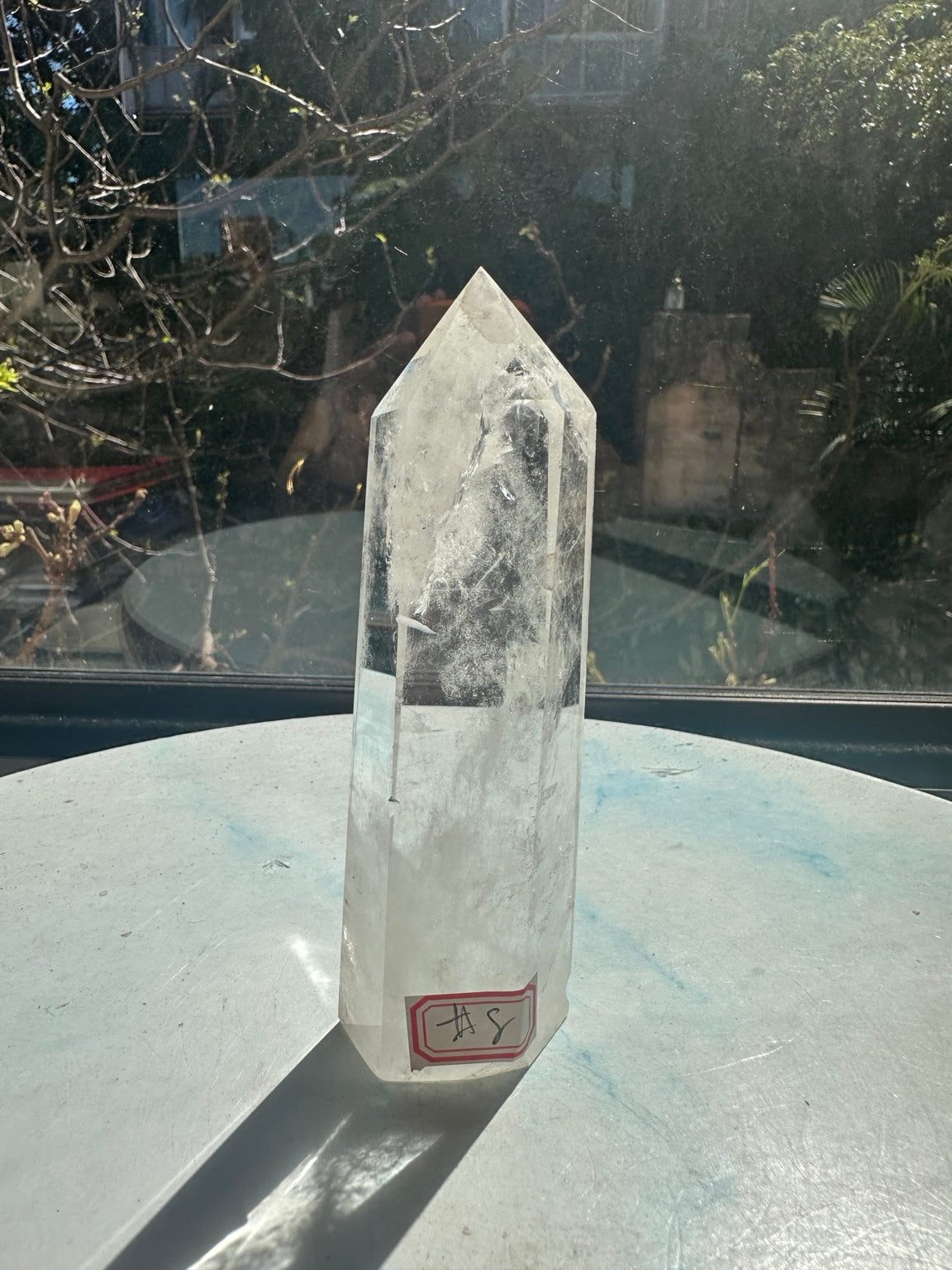 Brazilian clear quartz tower number 8, 232g and 13.2cm tall: front view with identifying label and long shadow in natural sunlight.