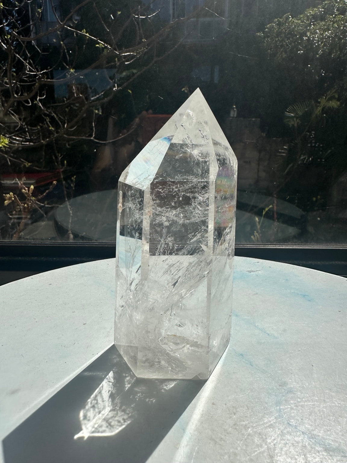 Side view of clear quartz tower number 7 with a small rainbow reflection on the right facet and natural internal fracture textures.