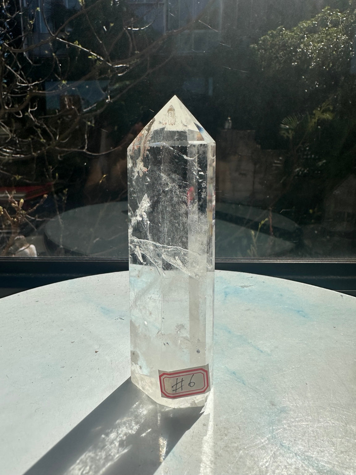 Full view of quartz tower number 7 standing on its flat base, with identifying label and long shadow in natural window light.