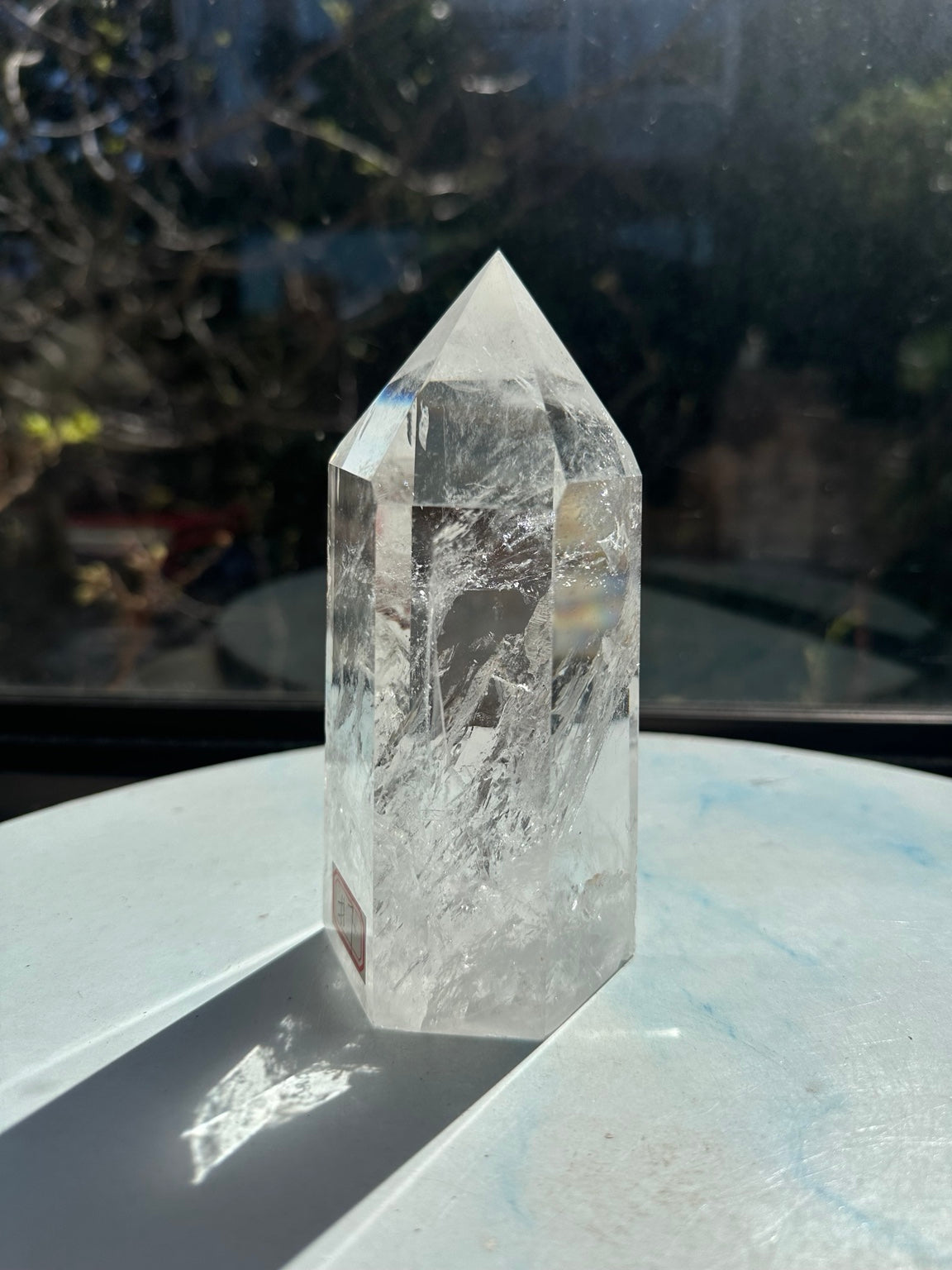 Angled view of the six-sided quartz tower showing broad polished faces and fine white internal patterns.