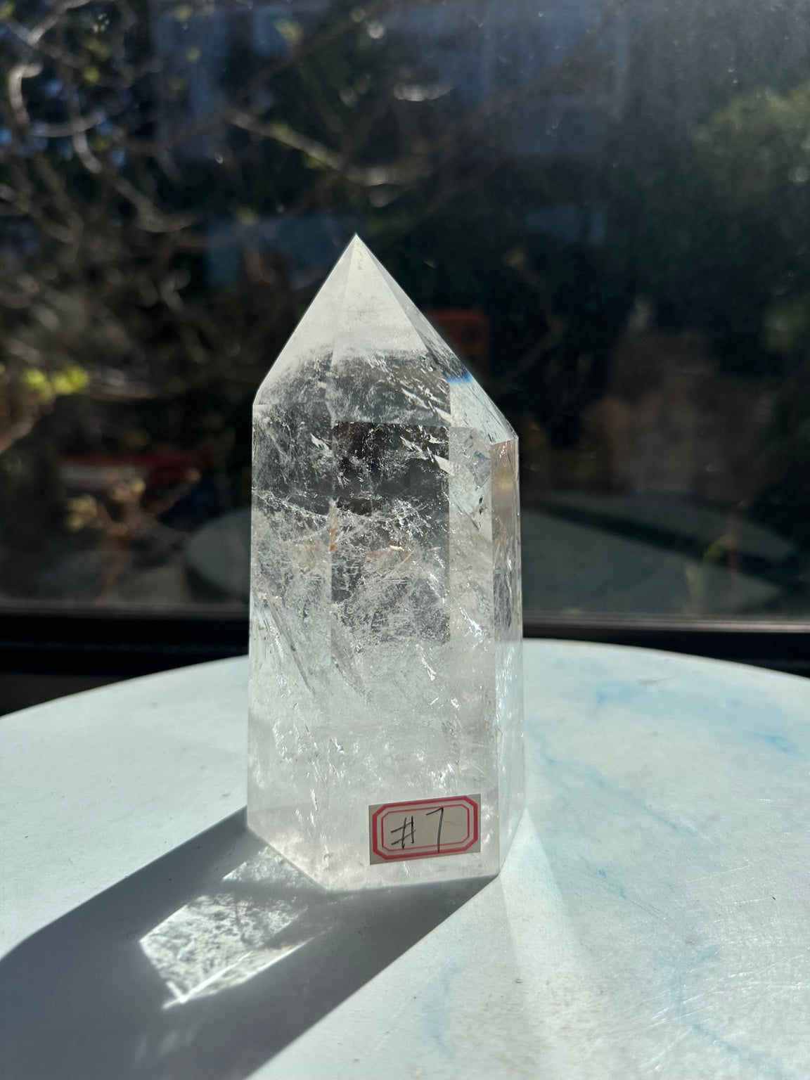 Front view of Brazilian quartz tower number 7 in sunlight, showing polished faces and white feather-like internal textures.