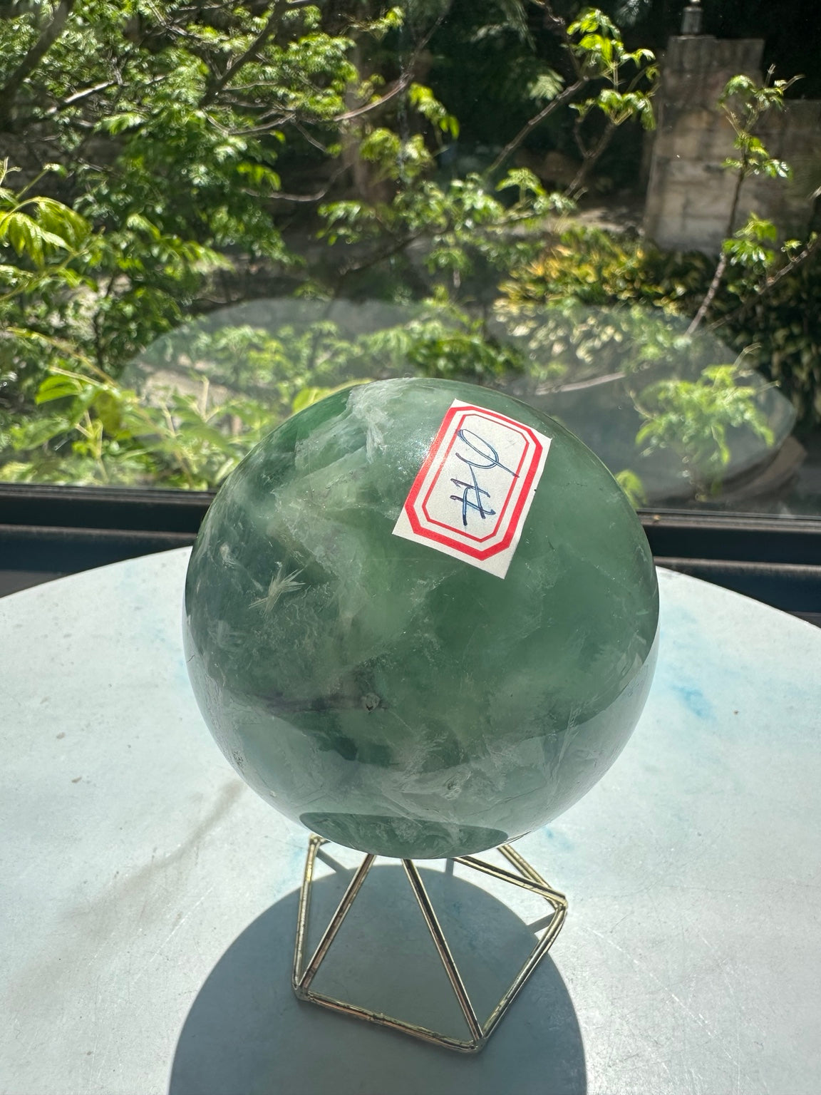 Unedited original photograph of exact 583g fluorite sphere No.4 with its red-bordered number label and stand