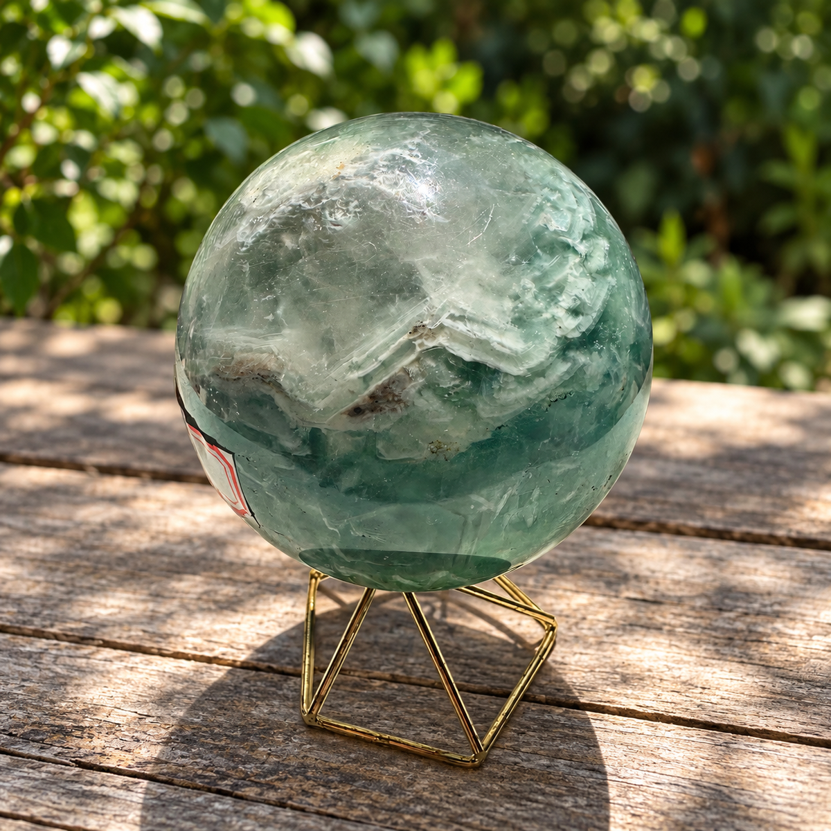 Layered side of Madagascar fluorite sphere with cream-grey bands and deep green zones