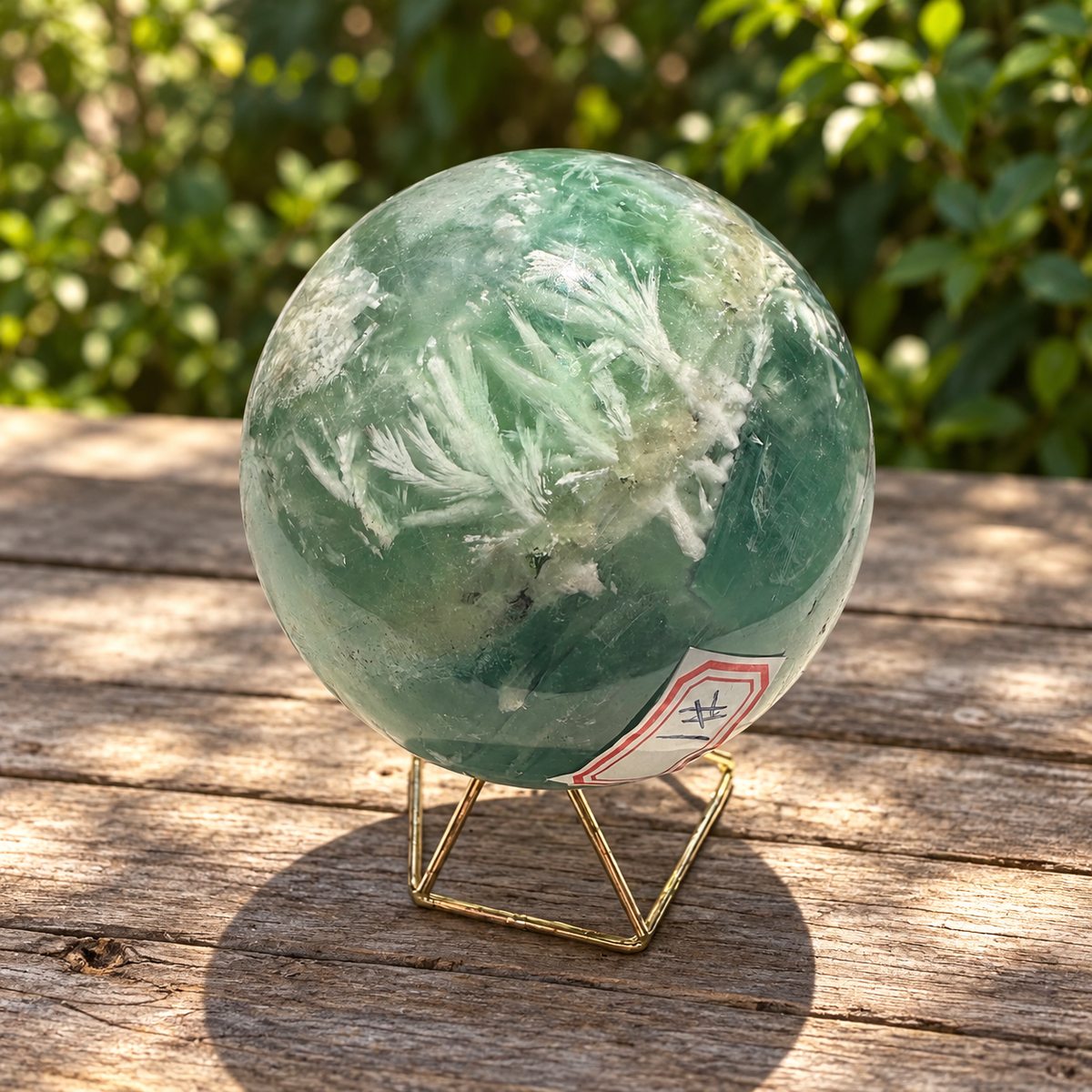 Close angle of white feather-like inclusions, dark natural marks and green zoning in sphere No.1