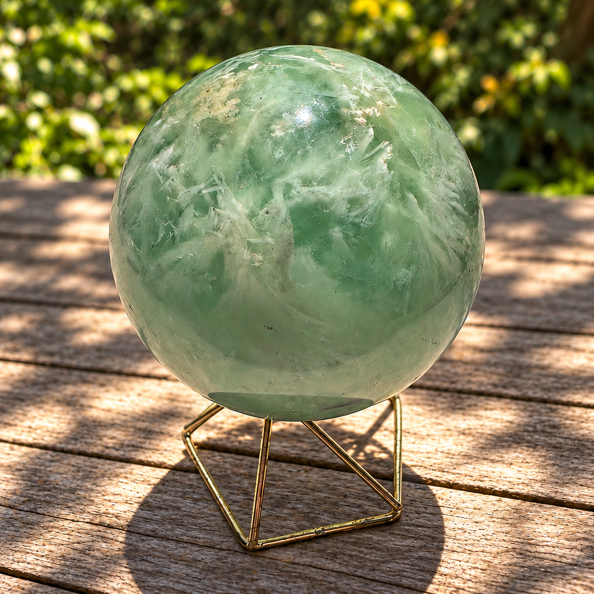 Green feather fluorite sphere No.2, 472g and 6.8cm diameter, on a geometric metal stand on a wooden table