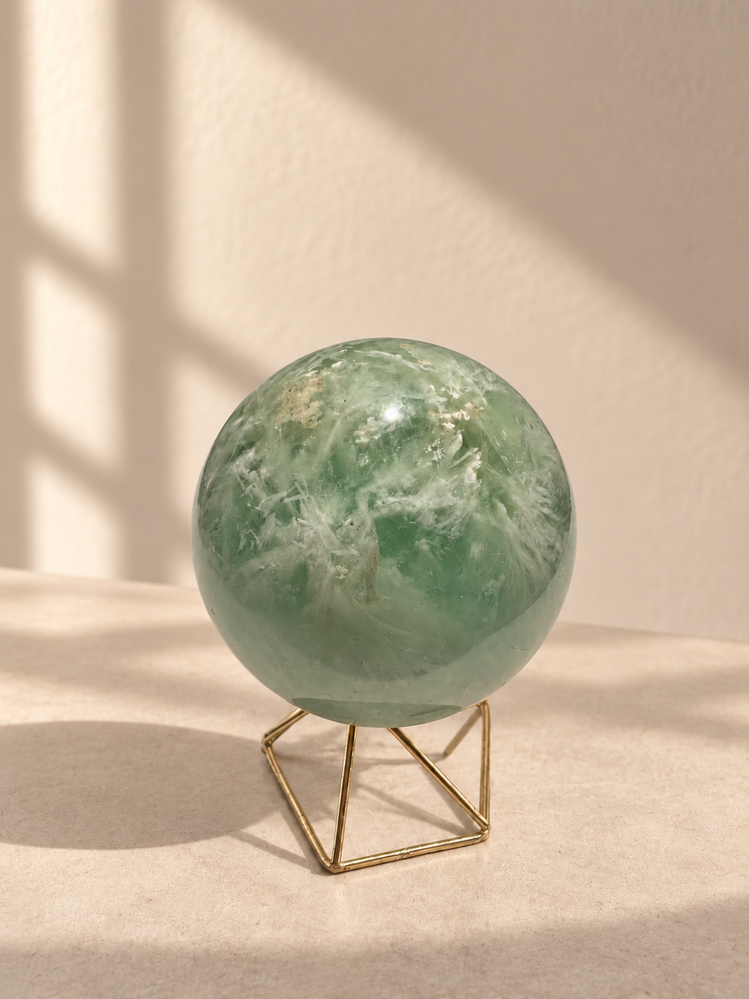 Feather fluorite sphere showing white feathery formations and a small natural tan inclusion