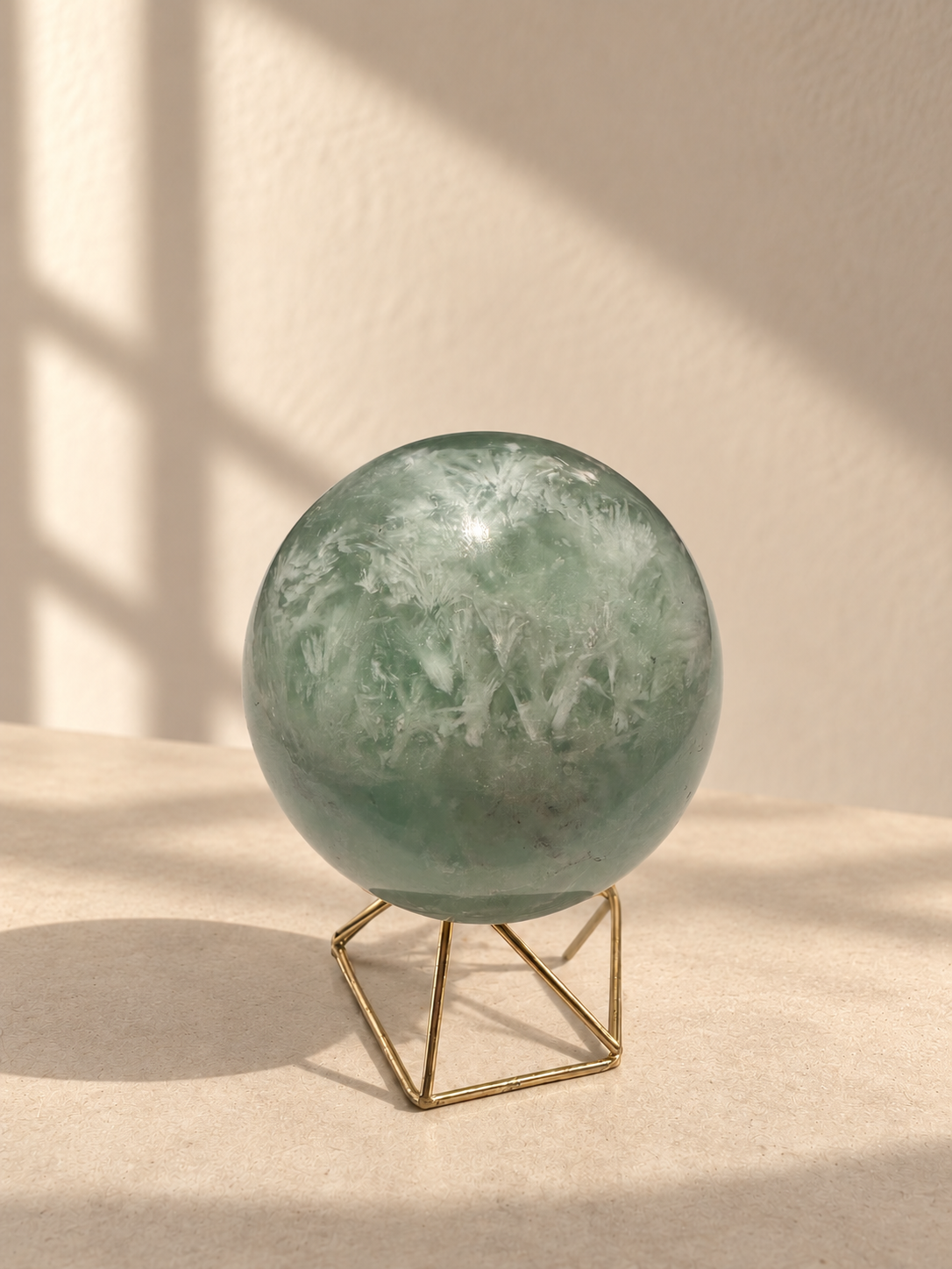 Side view of feather fluorite sphere with wispy white inclusions and natural dark flecks