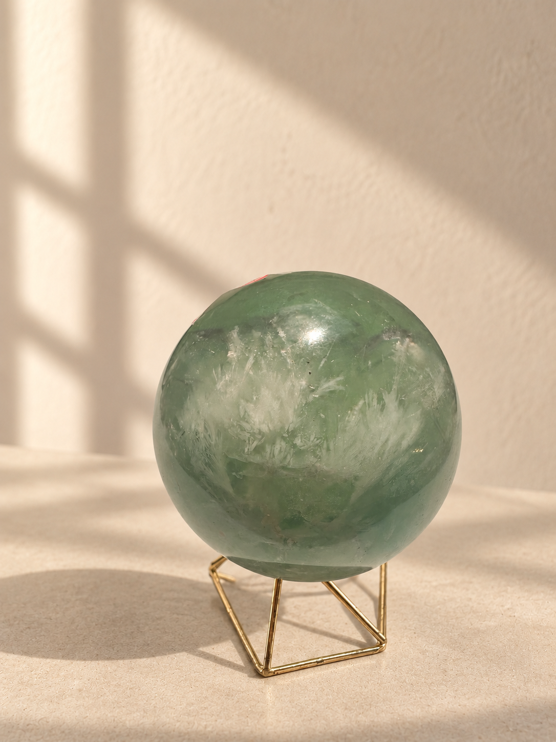 Alternate angle of pale green fluorite sphere with white feather patterns and visible natural marks