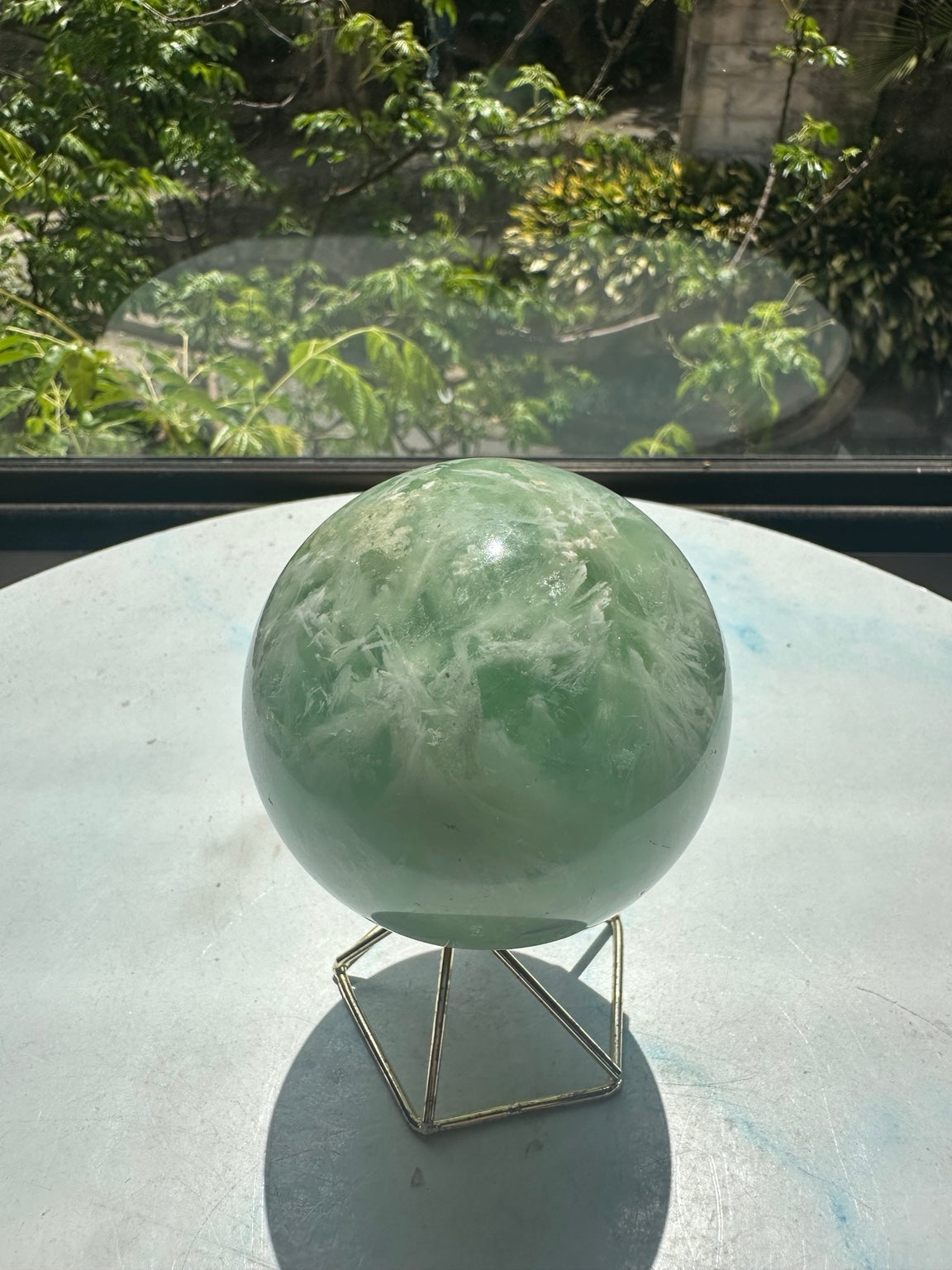 Unedited original photograph of feather fluorite sphere No.2 on its stand in natural window light